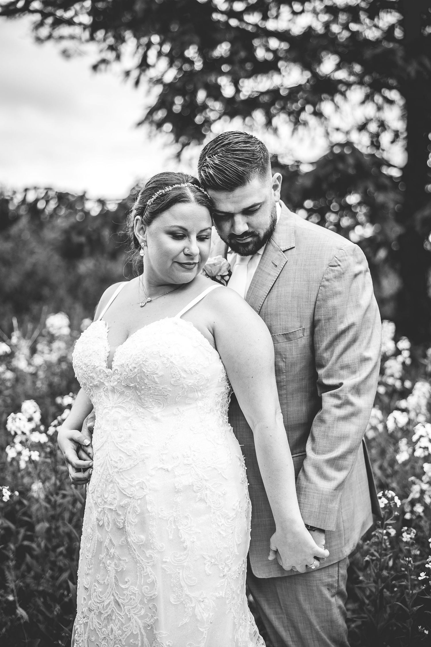 A black and white intimate portrait of newlyweds among blooming flowers and trees.