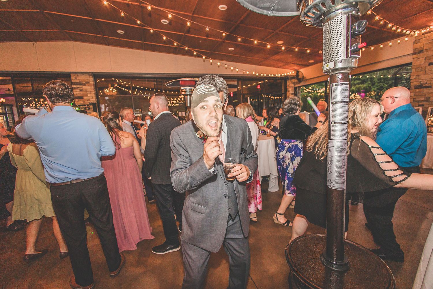 Wedding reception space with string lights creating warm ambiance across wooden ceiling.