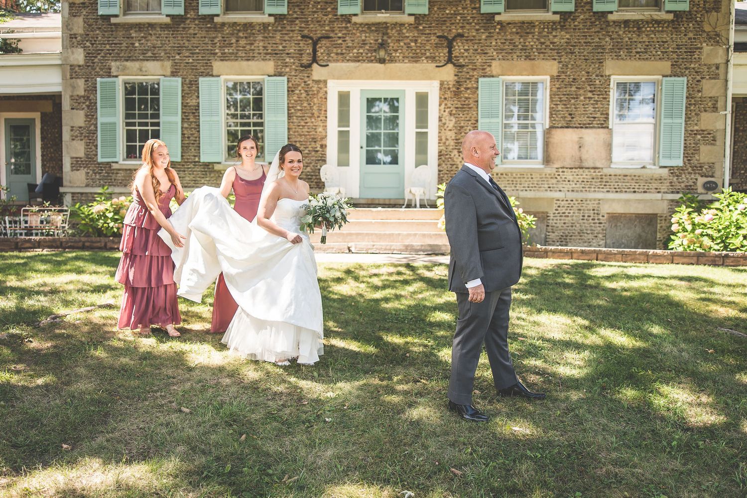 Wedding party poses in front of a historic brick building with blue shutters.