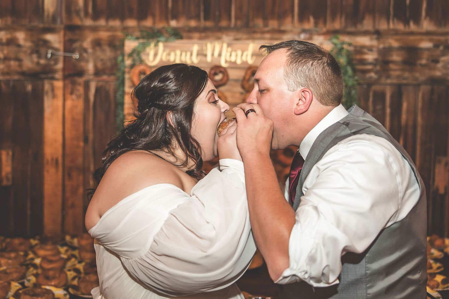 Candid shot of newlyweds sharing dessert at their rustic barn reception.