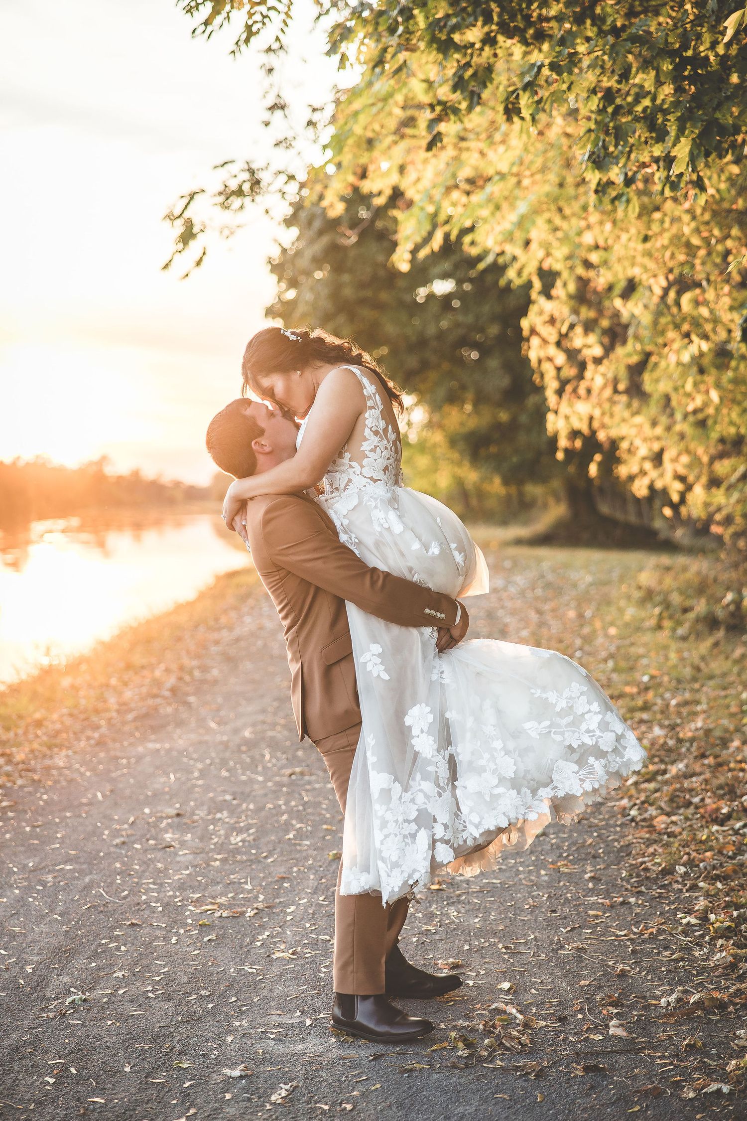 Romantic wedding couple poses during golden hour on a scenic outdoor path.