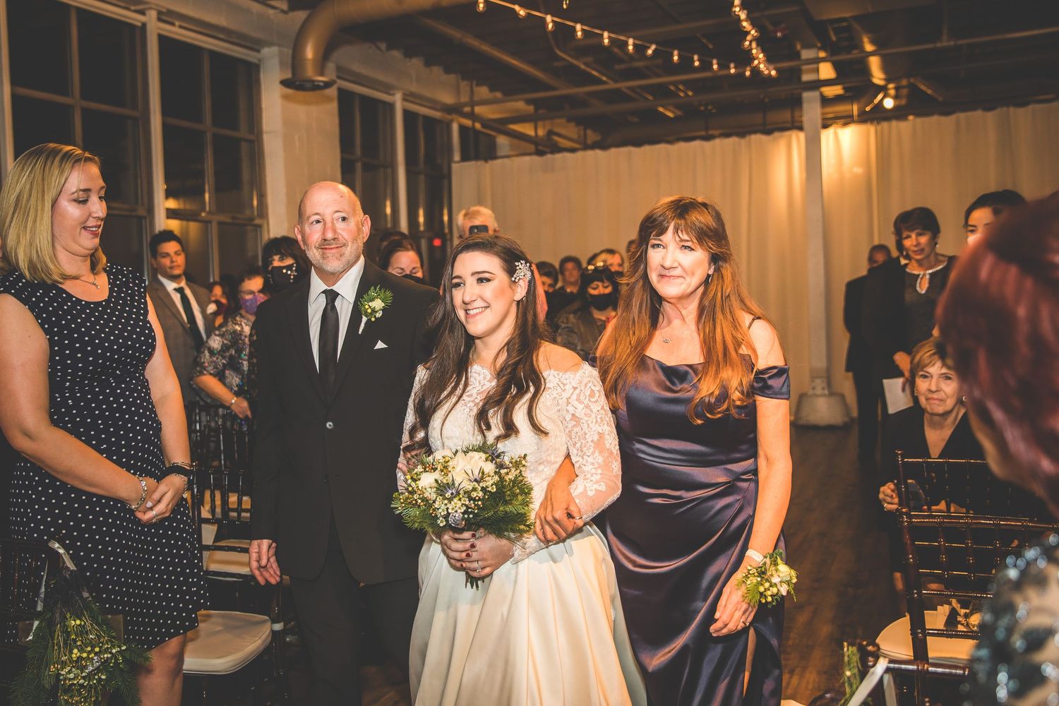 Wedding celebration in a modern venue with string lights and wooden accent walls.