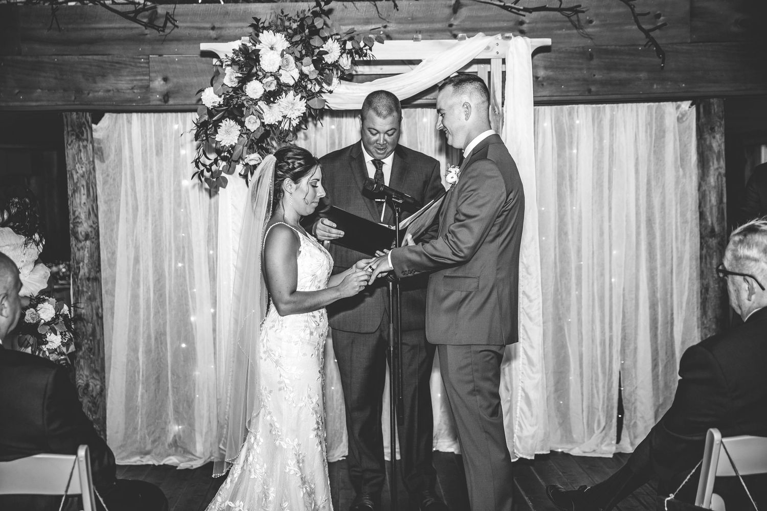 Black and white photo of couples dancing at an elegant wedding reception with decorative lighting.