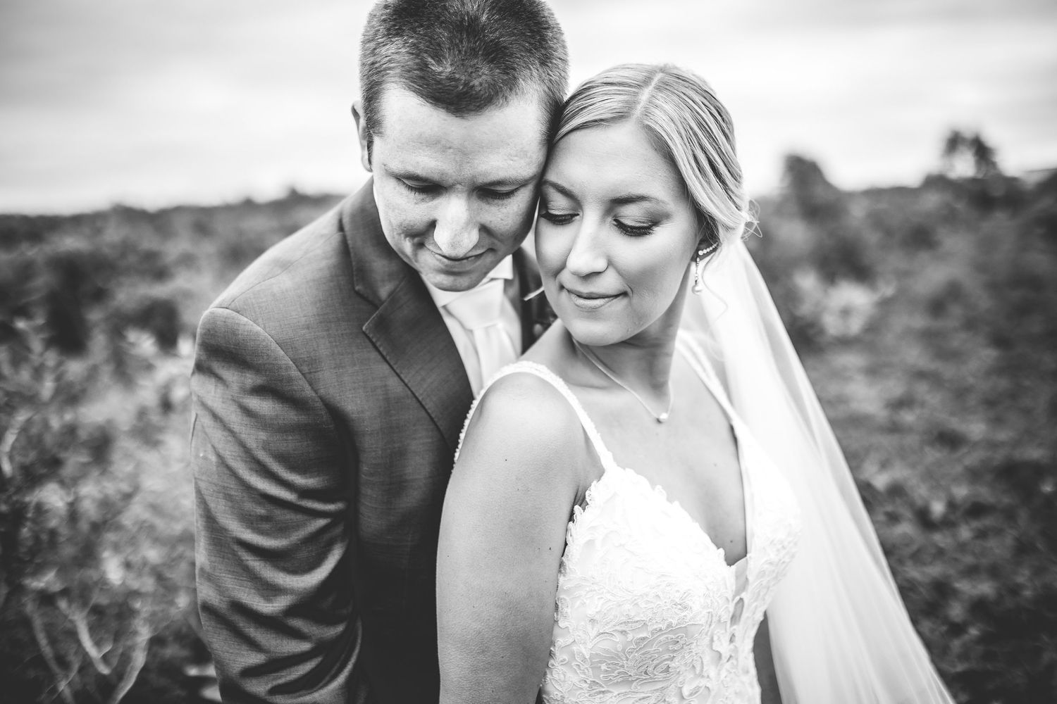 A romantic black and white wedding photo series showing tender moments between newlyweds in an outdoor setting.