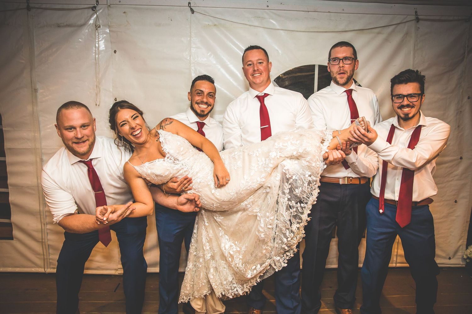 Wedding party members in red ties and dresses posing together for group photo.