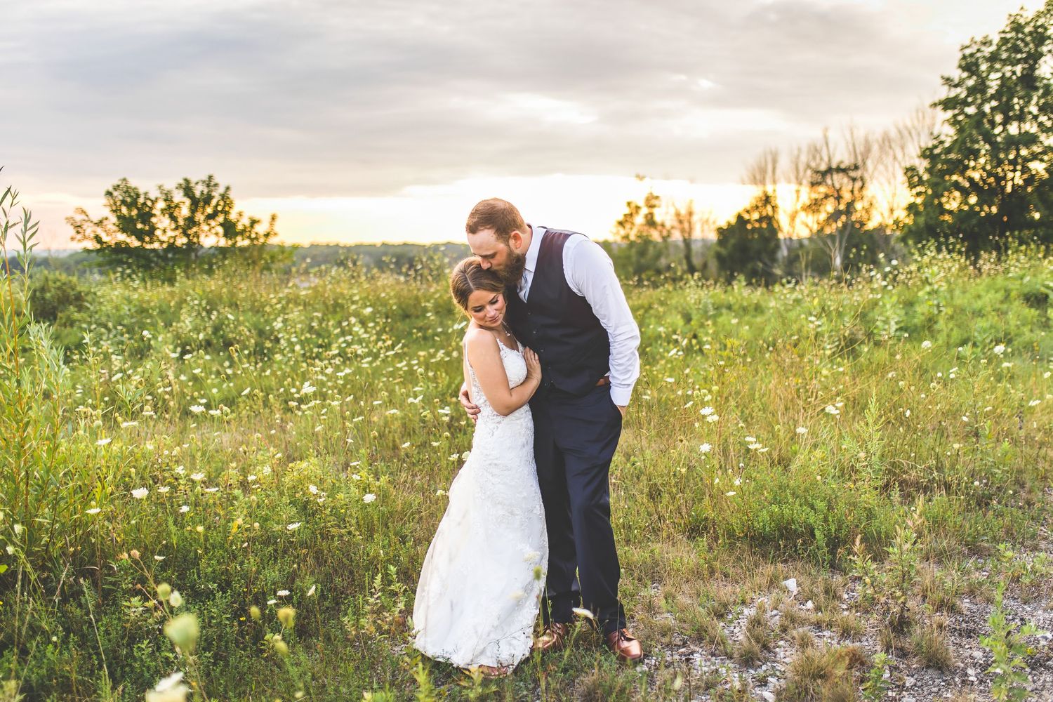 Newlyweds dance together in a field of wildflowers during golden hour.