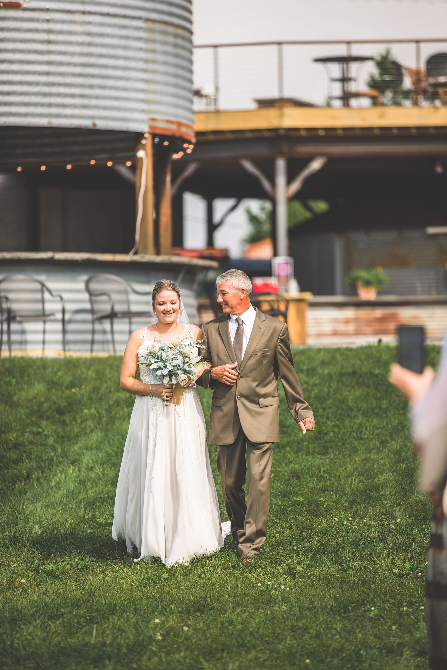 Outdoor wedding ceremony with rustic decor and string lights at a countryside venue.