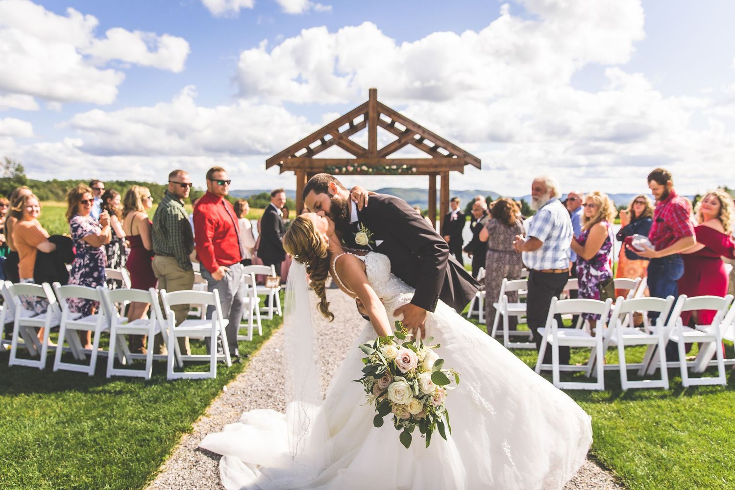A celebratory moment during a wedding ceremony under a rustic wooden pergola.