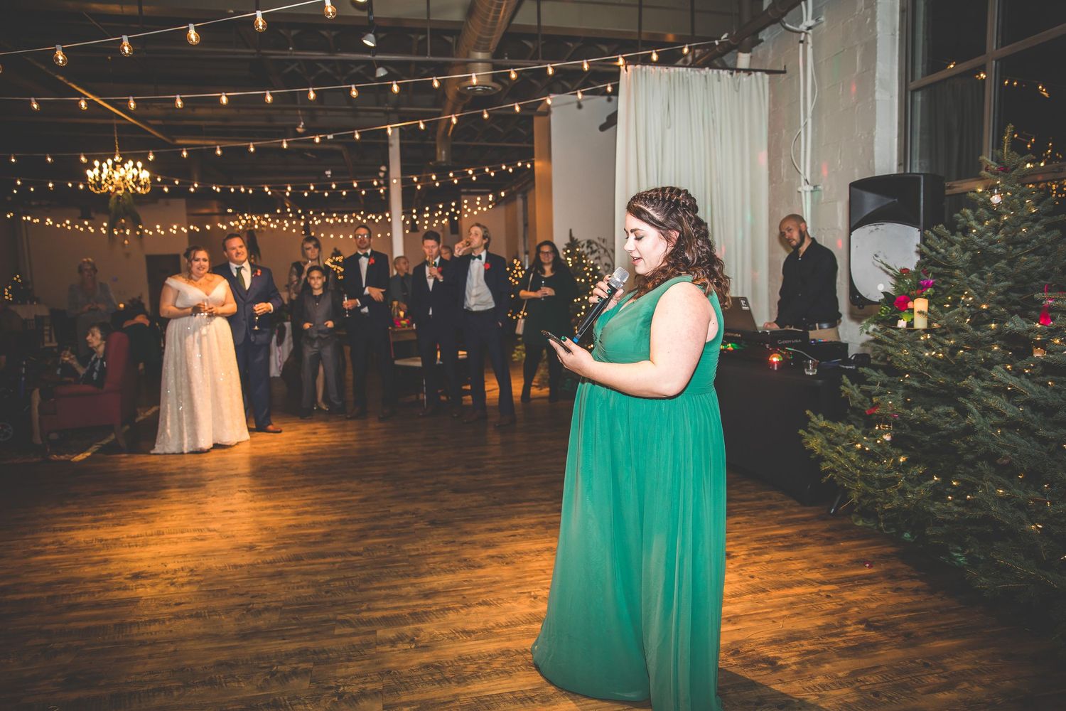 Wedding reception venue decorated with string lights and Christmas trees for a winter celebration.
