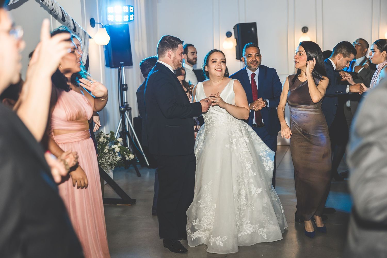 Couples dancing together during a wedding reception in a dimly lit ballroom setting.