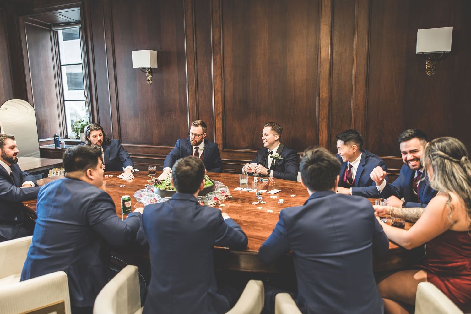 Business professionals gathered around a conference table in a wood-paneled meeting room.