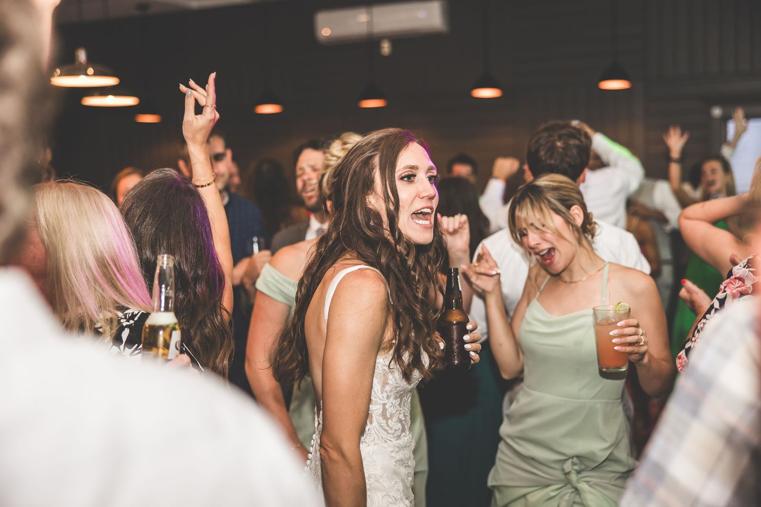 Wedding reception guests dancing and celebrating on a crowded dance floor.