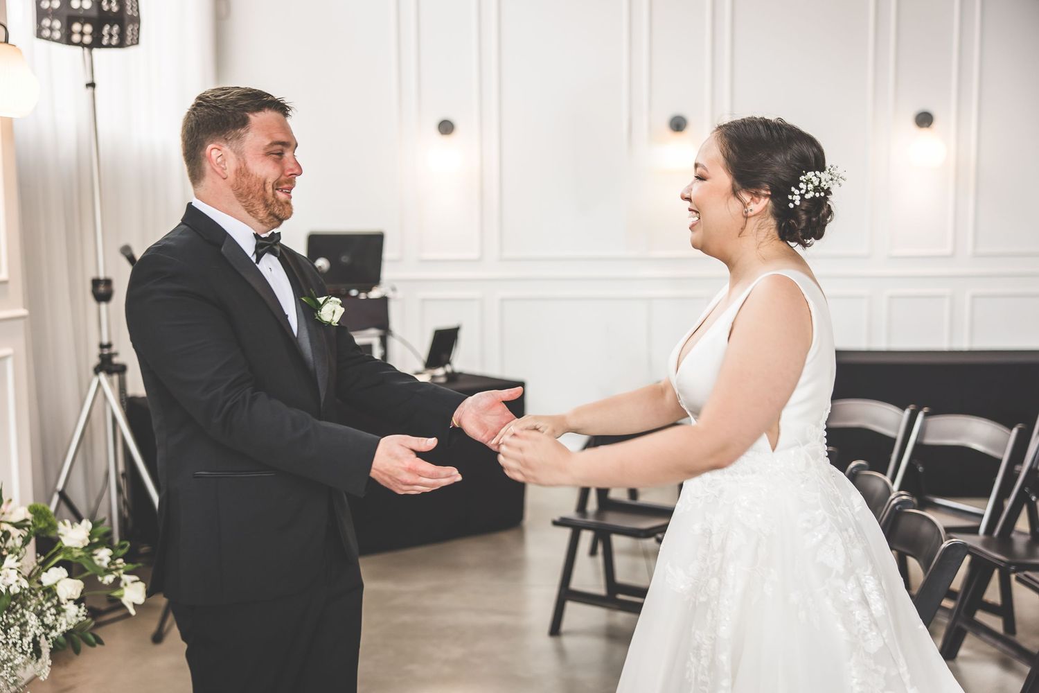 Couple laughing together during their wedding first look in a bright indoor venue.