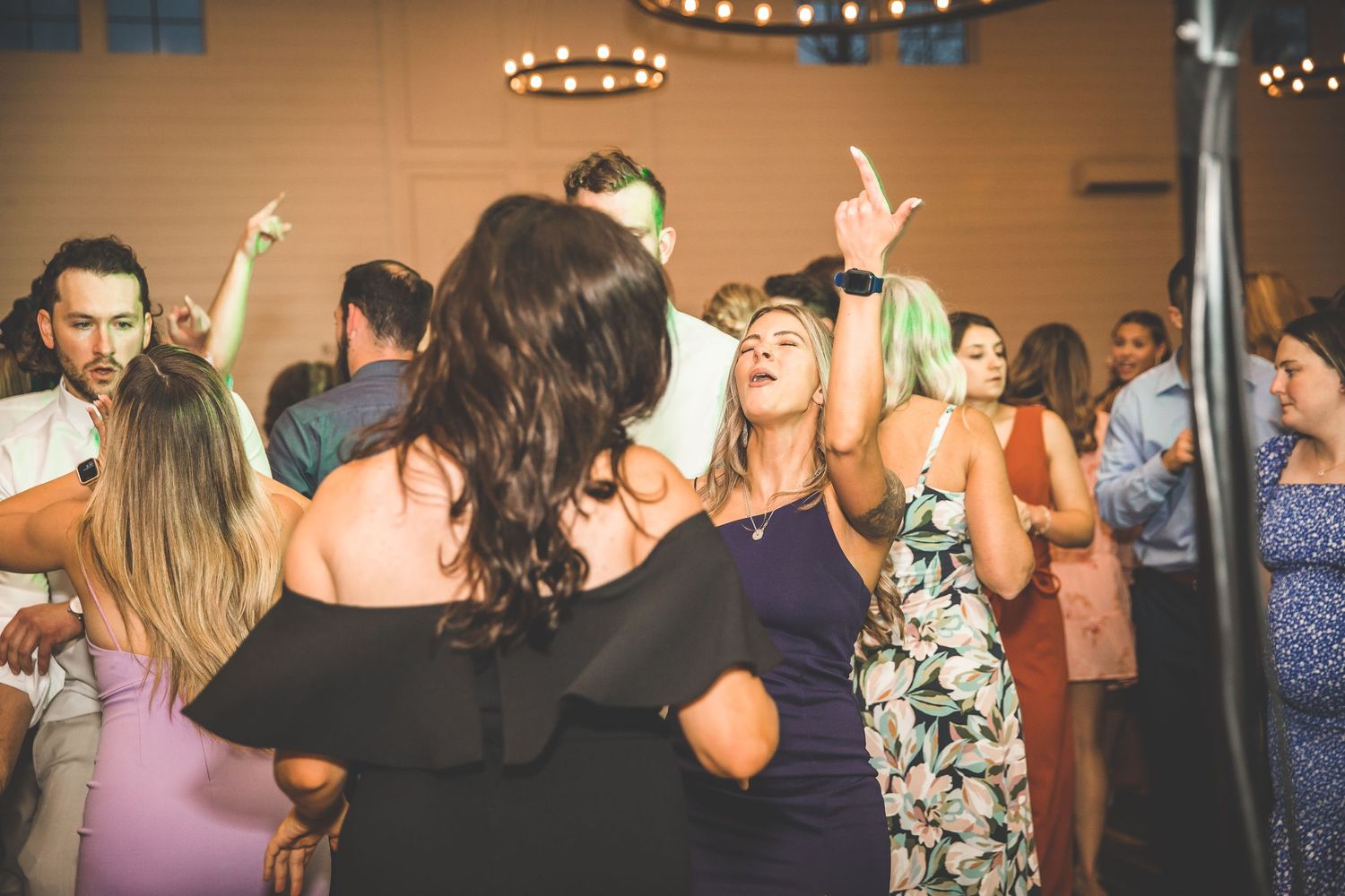 Party guests dancing and celebrating with hands in the air at a wedding reception.