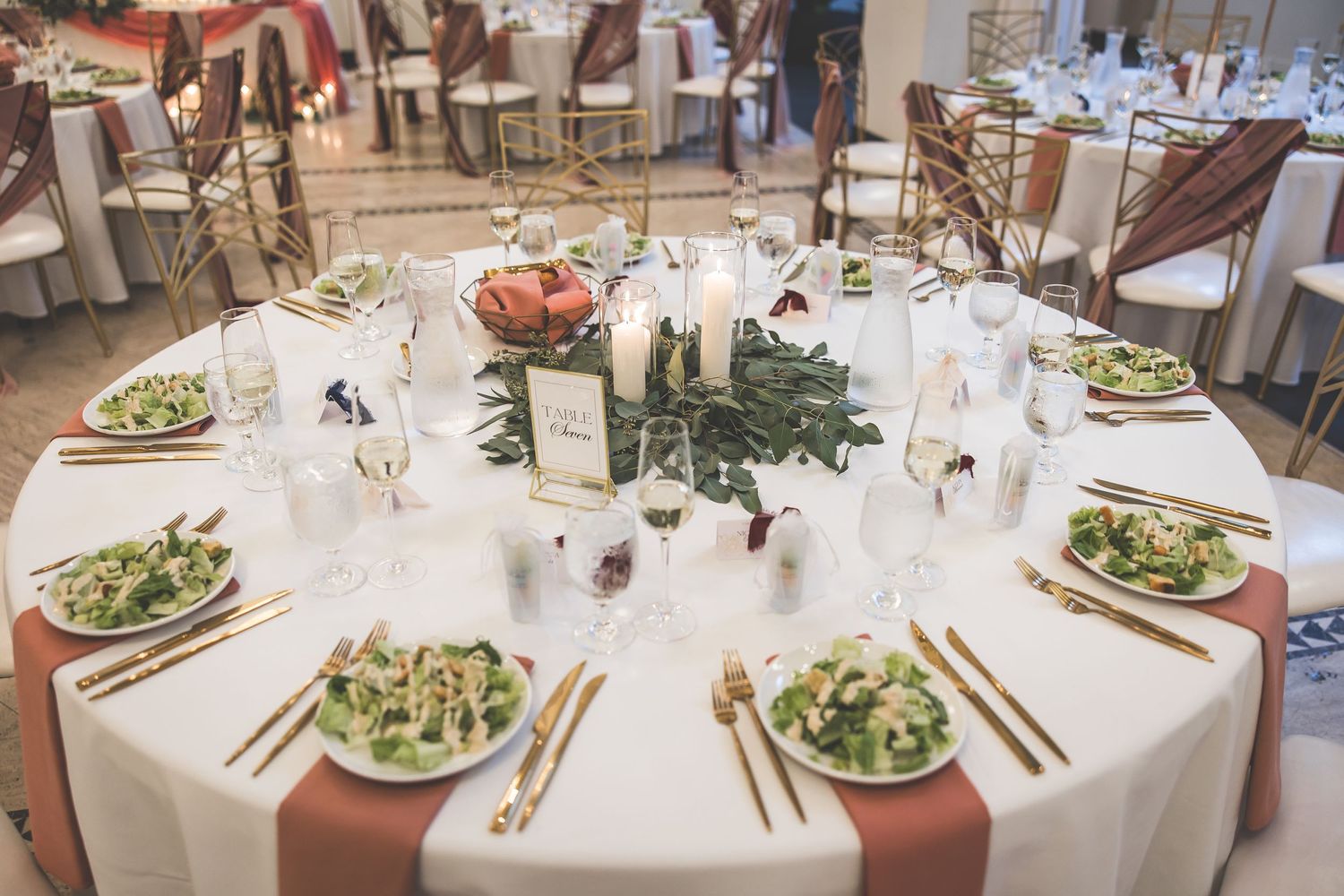 Overhead view of wedding reception tables set with salads and formal place settings.