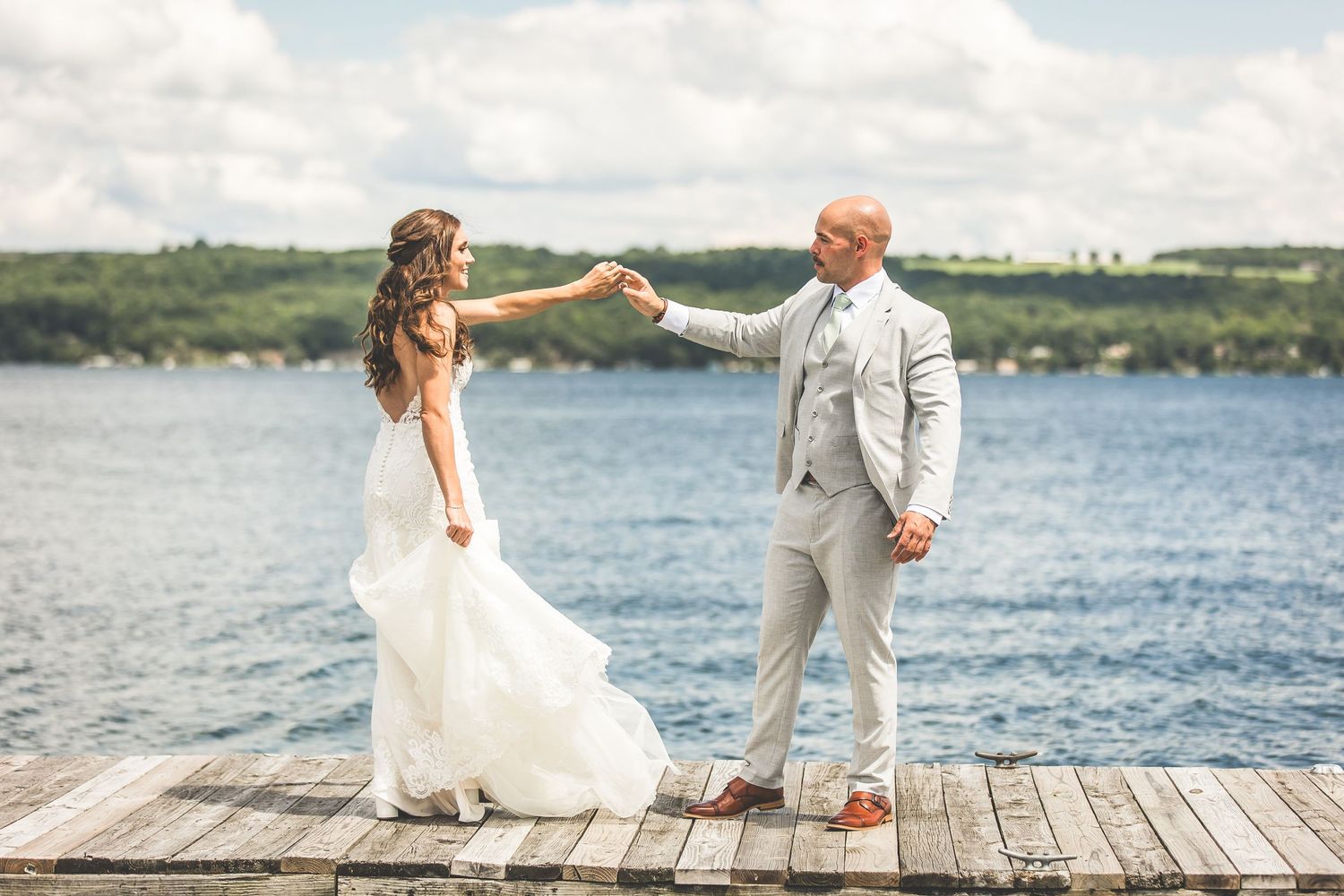A couple shares a romantic moment on a wooden dock overlooking a lake.
