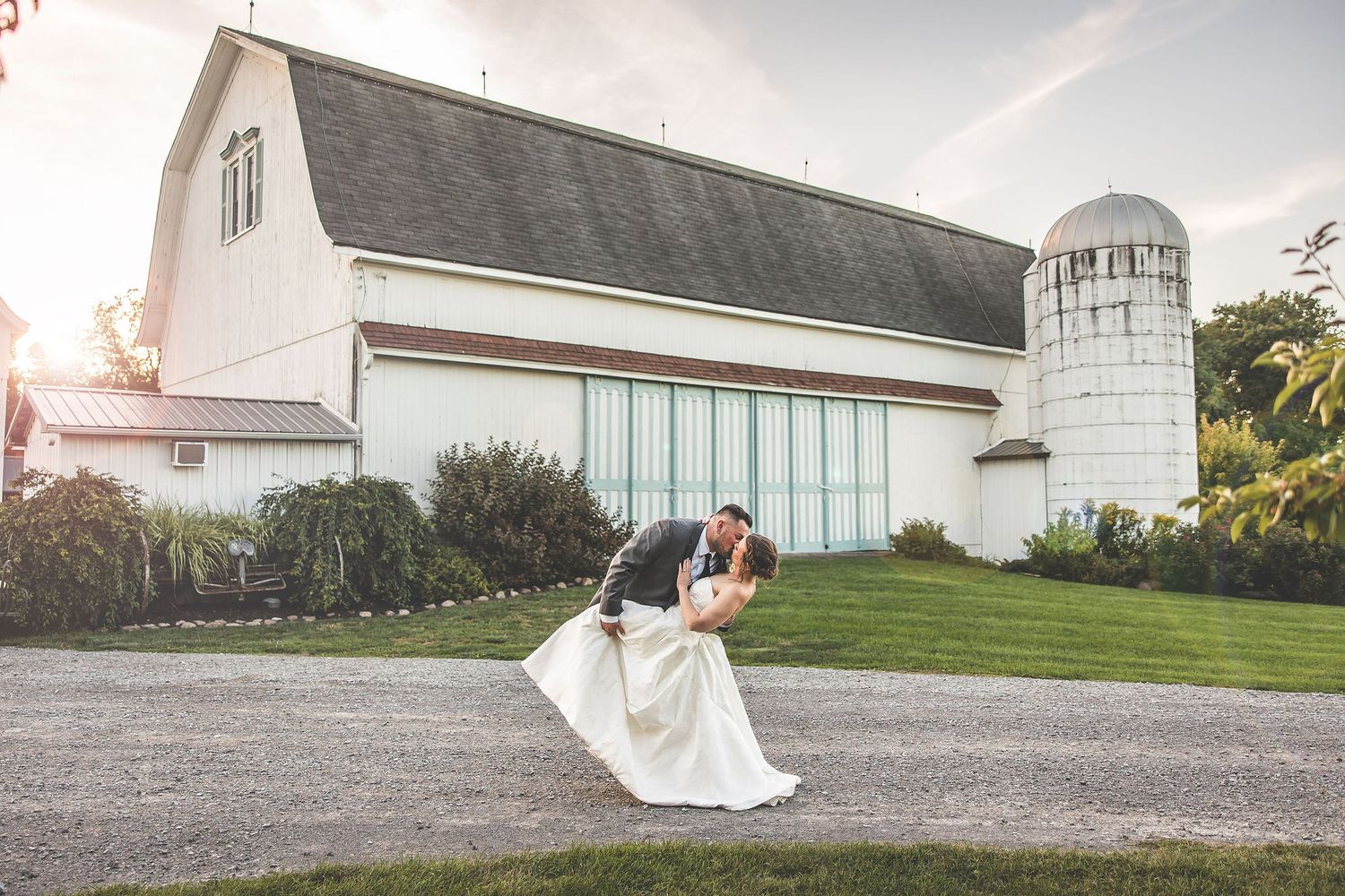 Wedding venue exterior featuring white church buildings and gravel pathways at sunset.