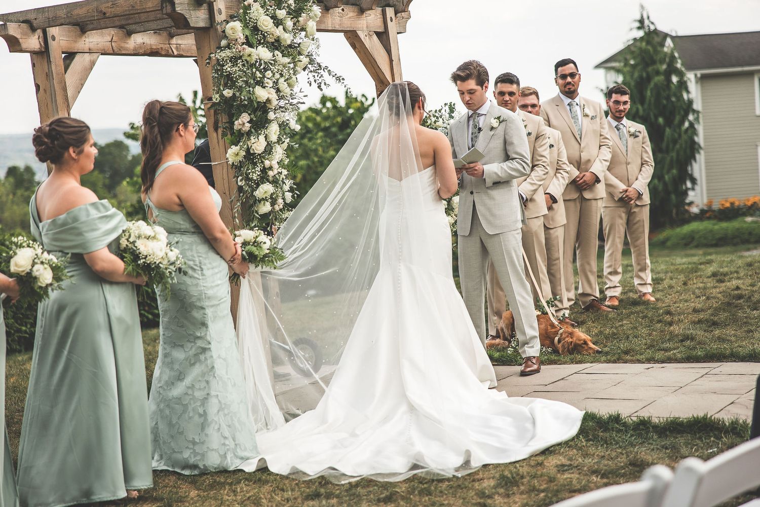 Wedding ceremony setup with rustic wooden arch and white floral arrangements.