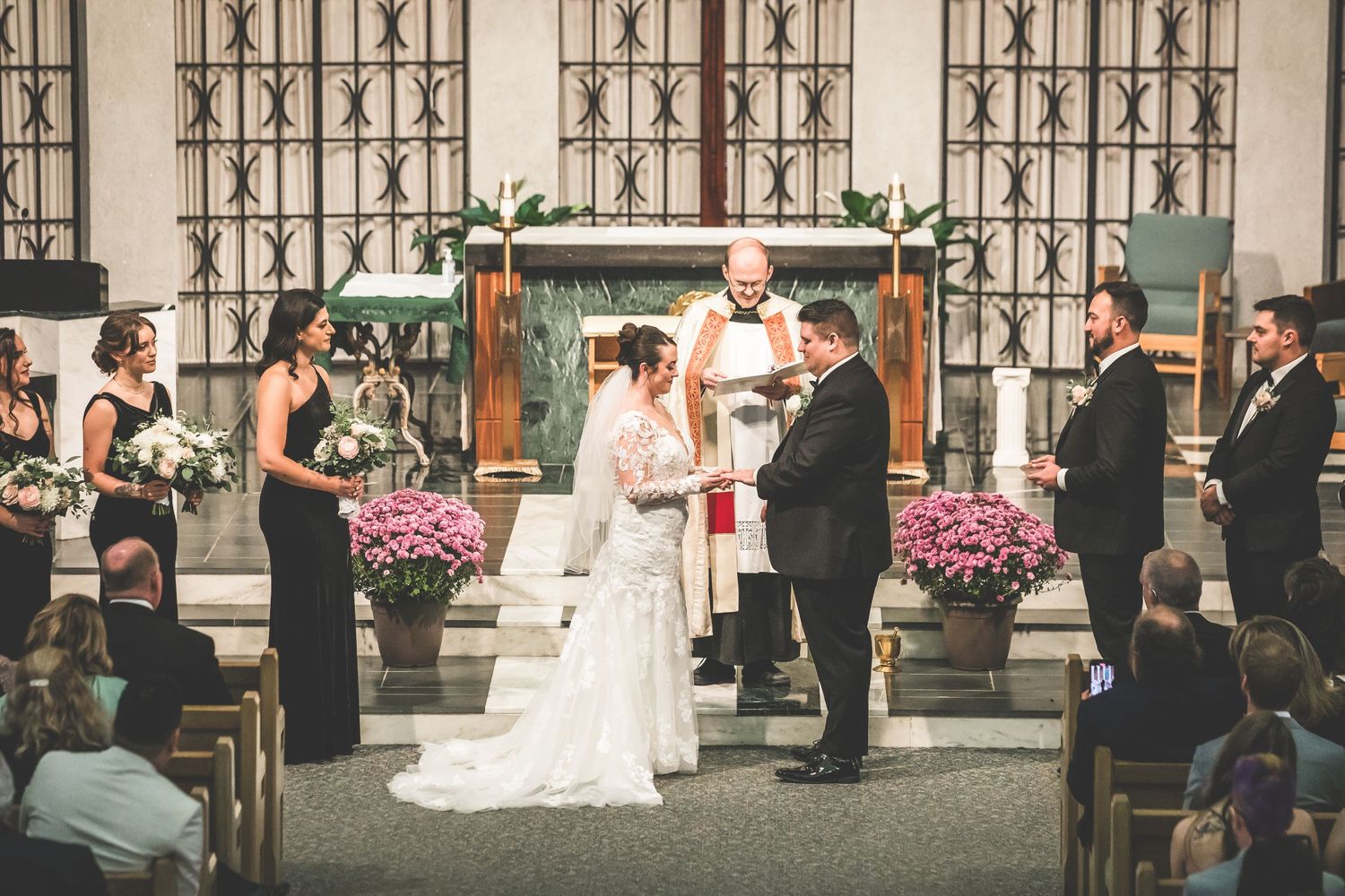Wide shot of wedding ceremony in church with guests seated and couple at altar.