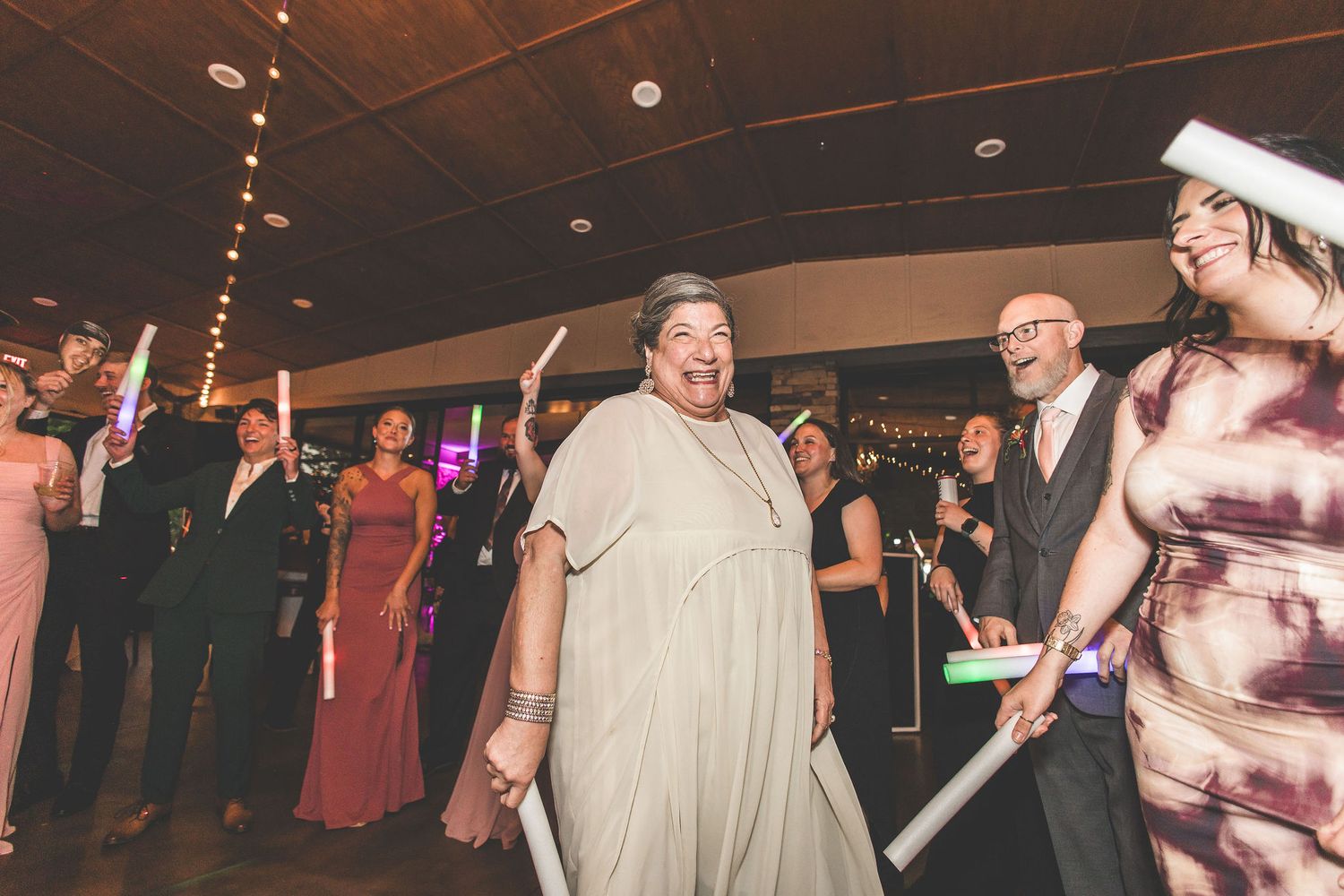 Wedding reception venue decorated with string lights and filled with dancing guests.
