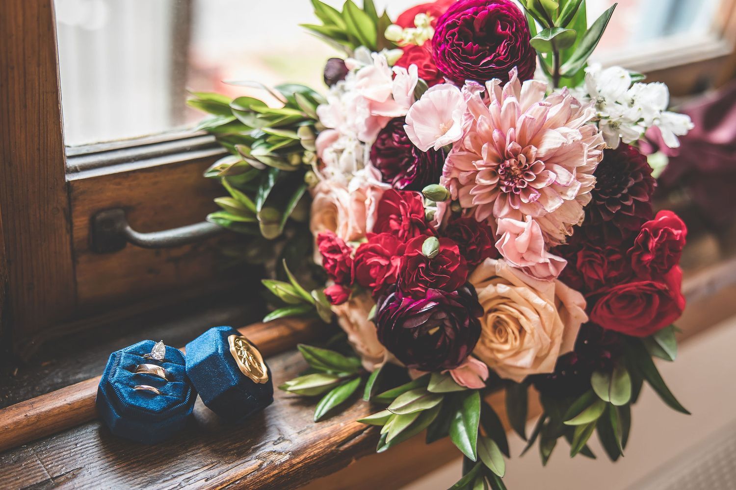 Colorful wedding florals featuring pink and burgundy blooms arranged on windowsill.