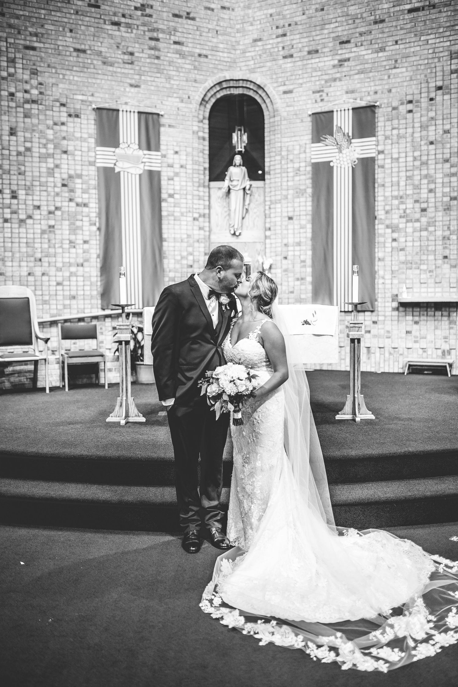 Black and white wedding ceremony moments captured in church with dramatic lighting.