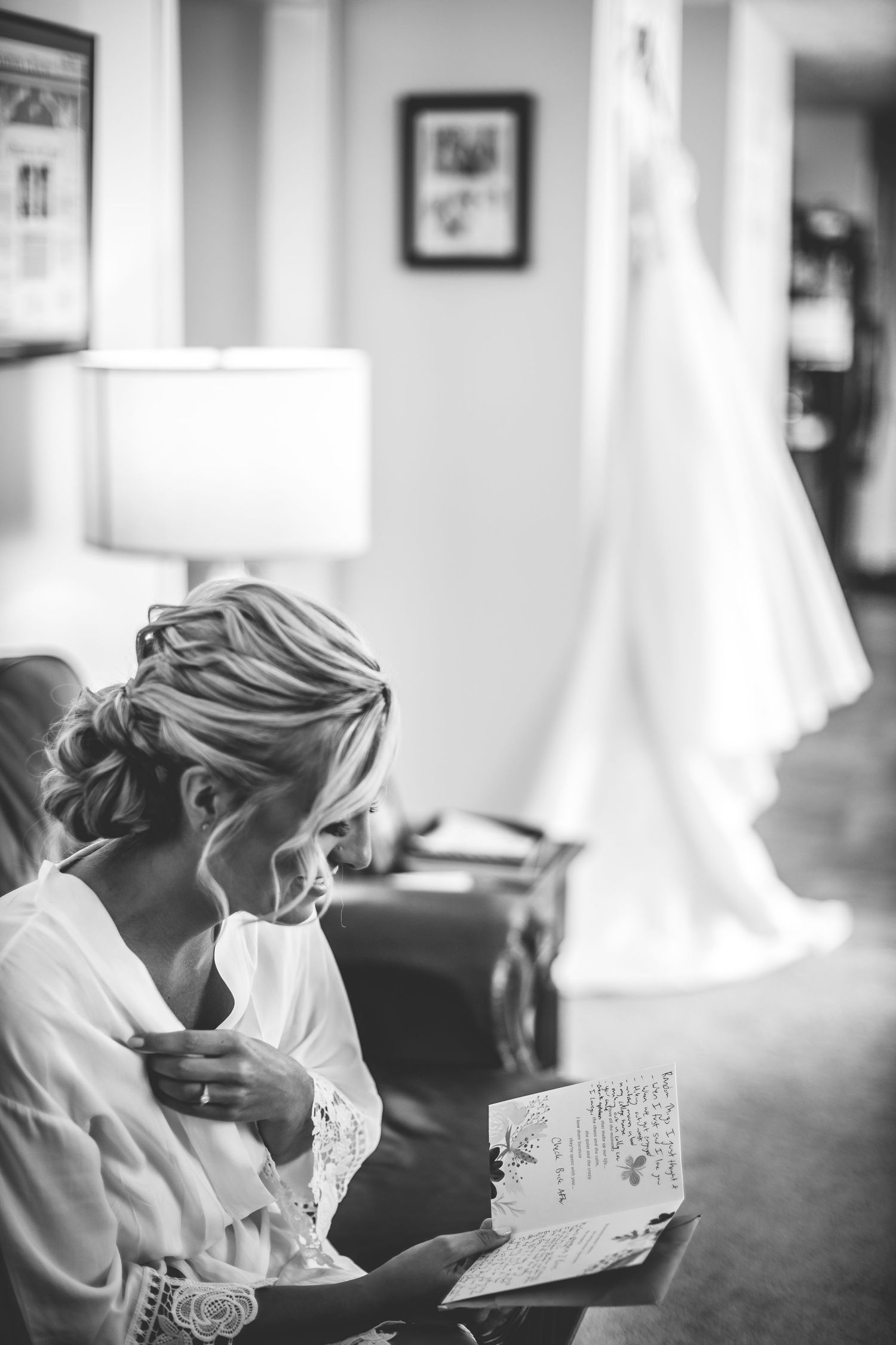 Black and white image of person reading letter while getting ready for wedding.