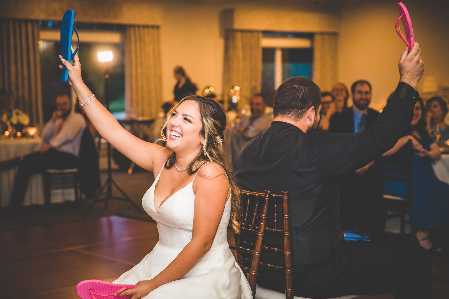 Guests enjoying a lively dance party at an indoor wedding reception venue with warm lighting.