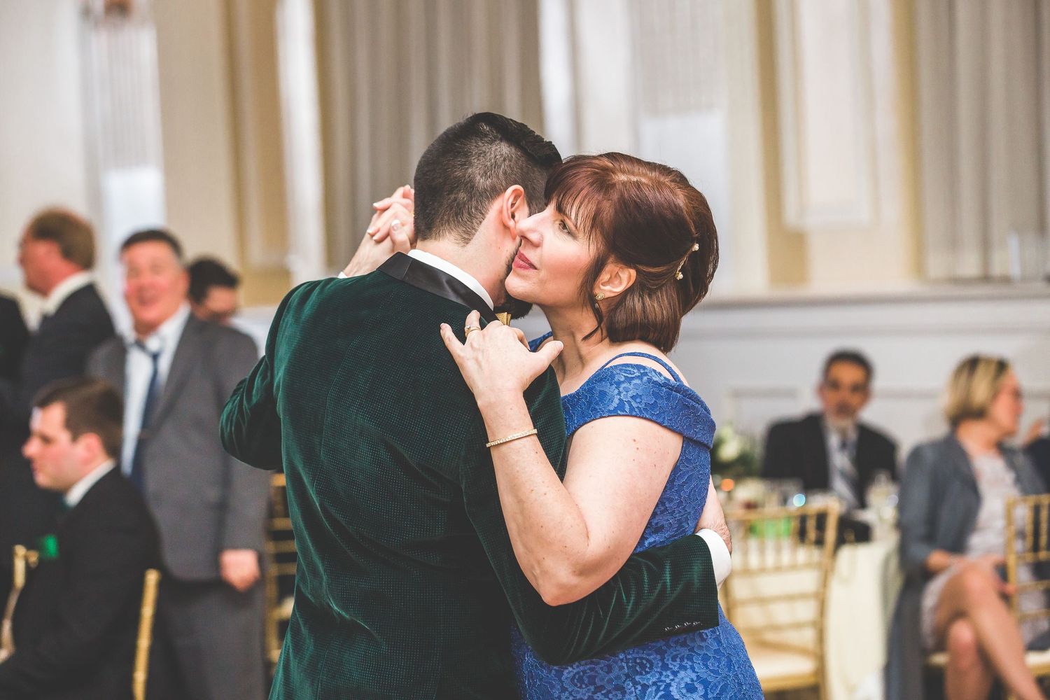 Guests celebrating during wedding reception speeches in an ornate ballroom venue.