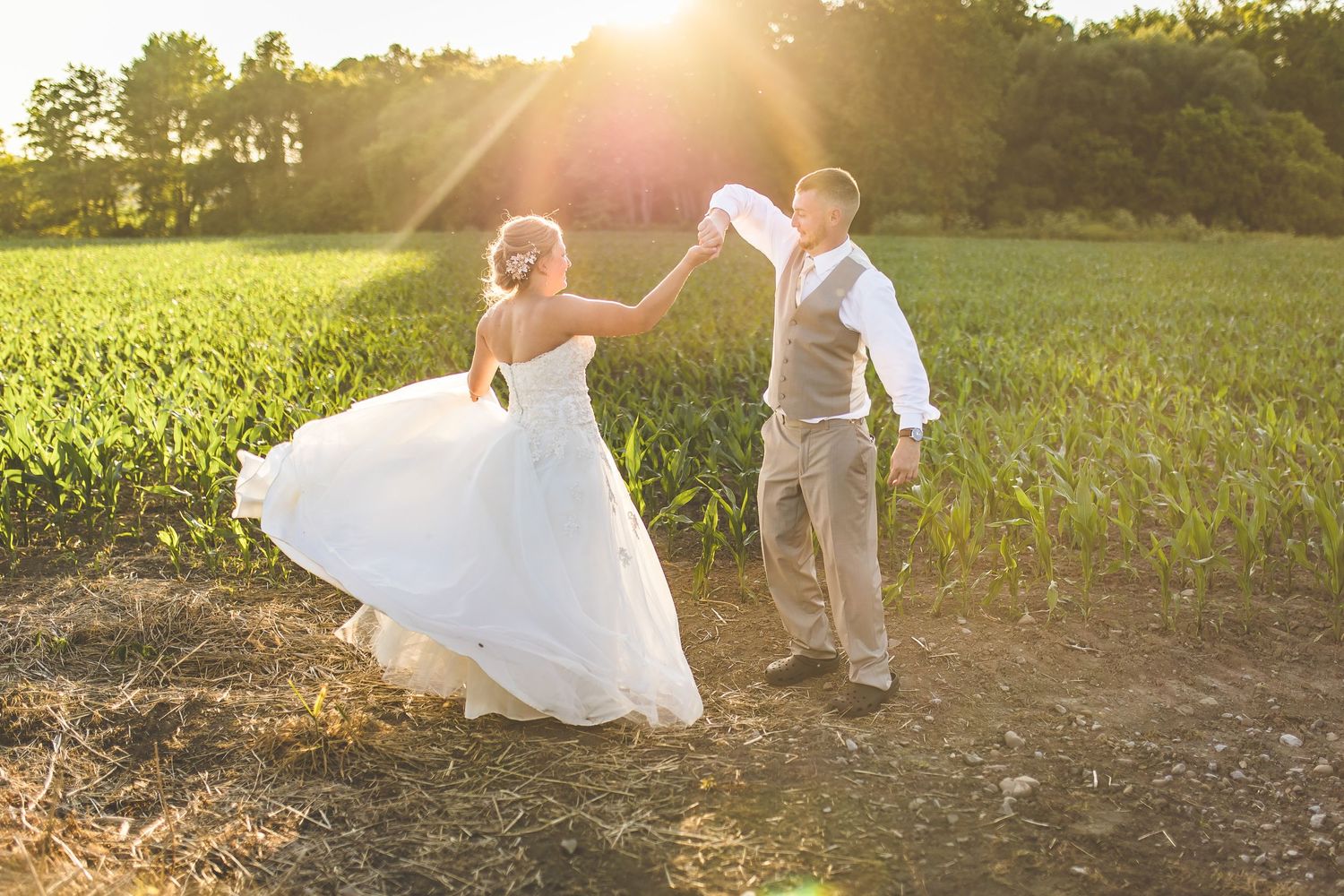 Couple dancing together in a field at sunset during their wedding photoshoot.