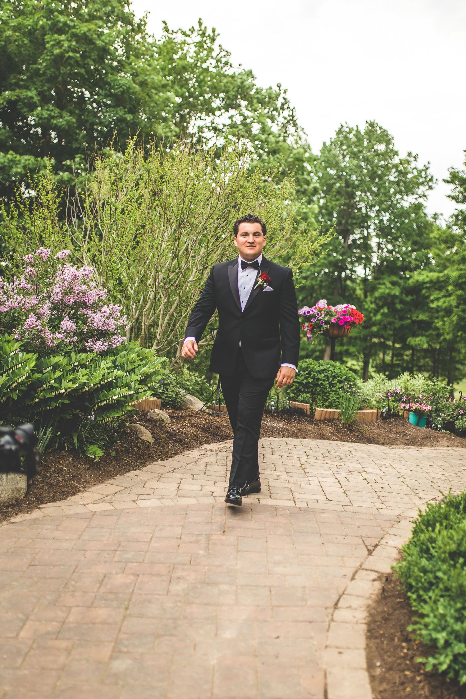 Stone pathway through a landscaped garden with blooming flowers and greenery.
