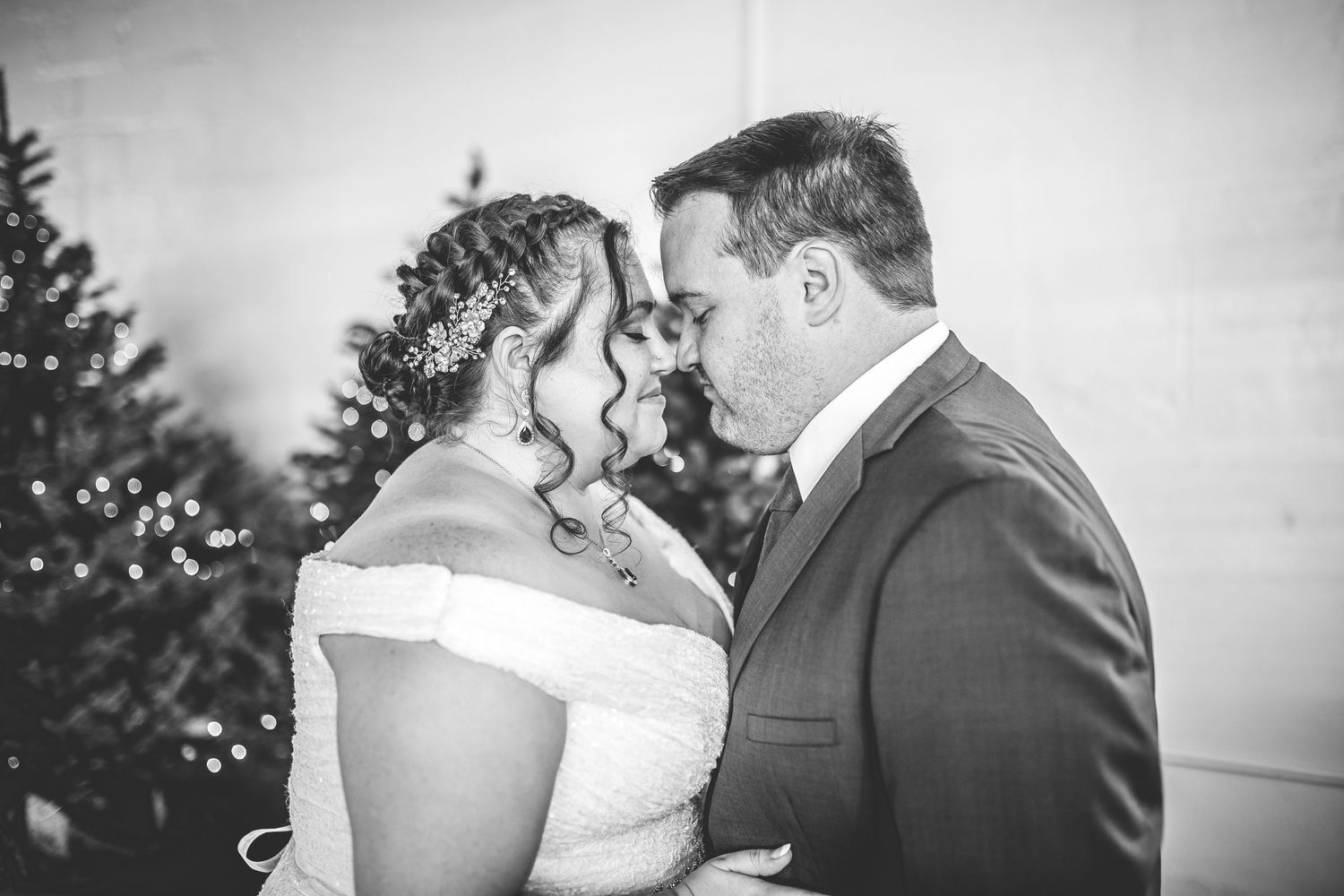 A tender wedding moment captured in black and white with pine trees as backdrop.
