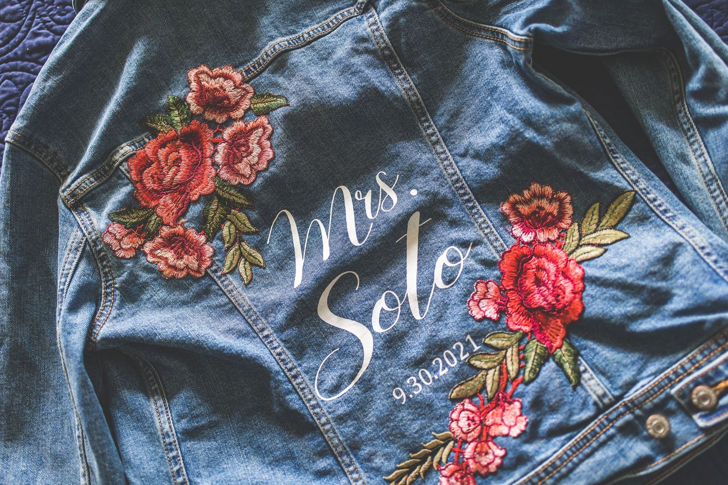 Custom denim jackets with floral embroidery and script text for wedding party.