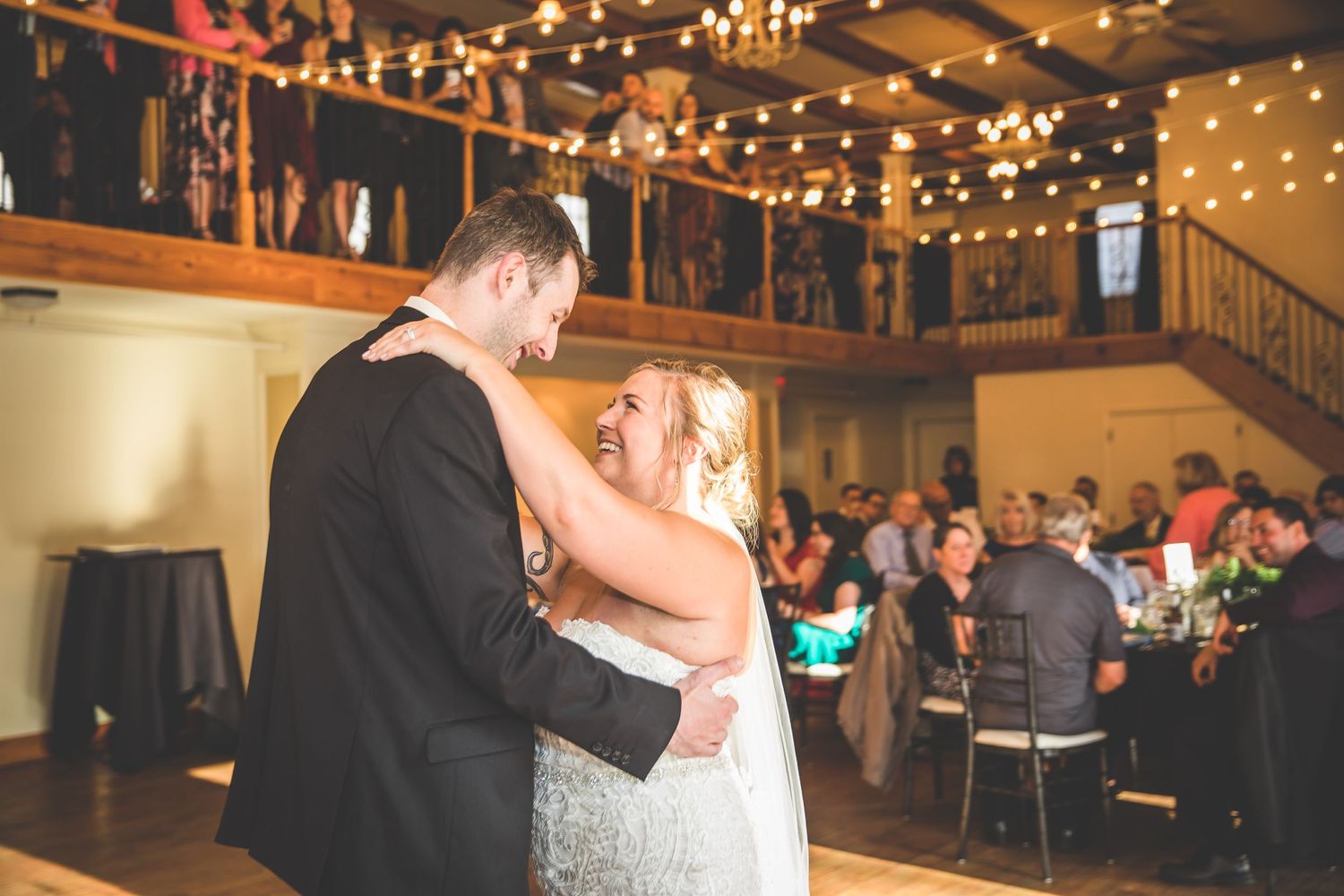 Reception hall decorated with romantic string lights and wooden beams for evening celebration.
