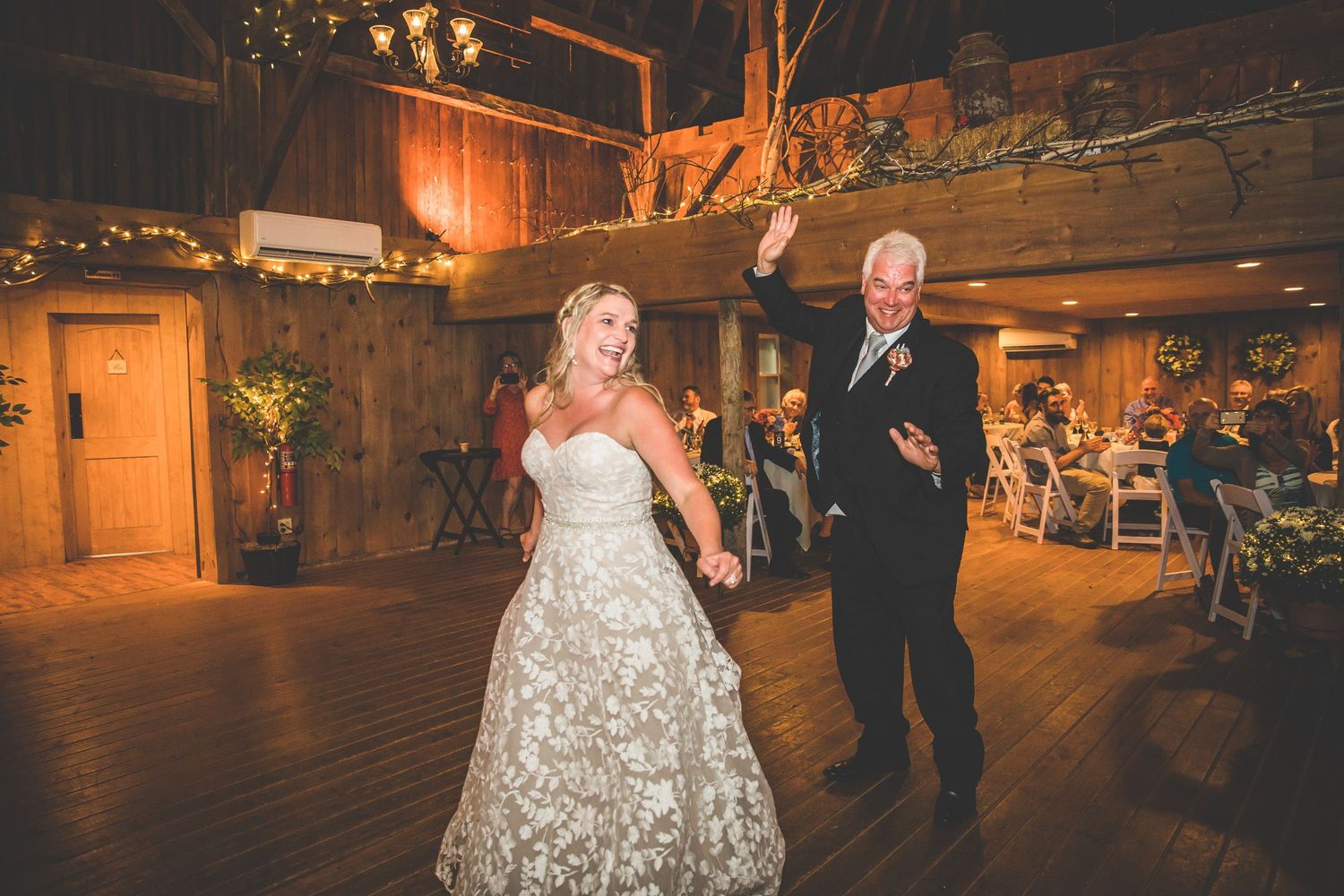 Wedding celebration in a rustic wooden barn with romantic lighting and dancing couples.
