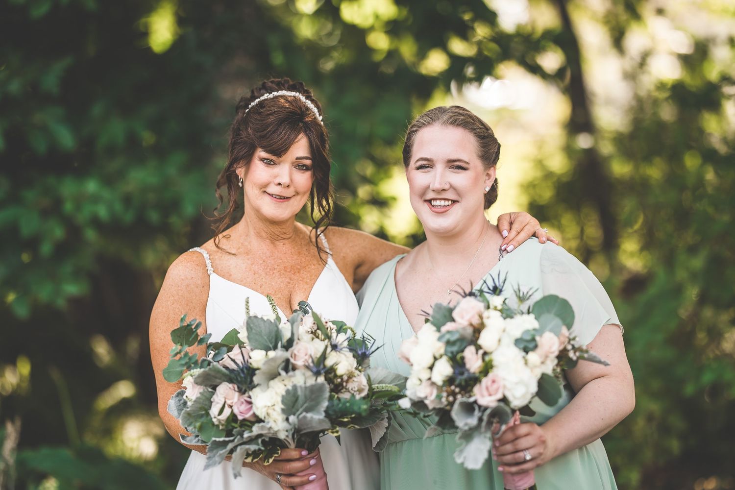 Bridesmaids in sage green dresses hold white floral bouquets.