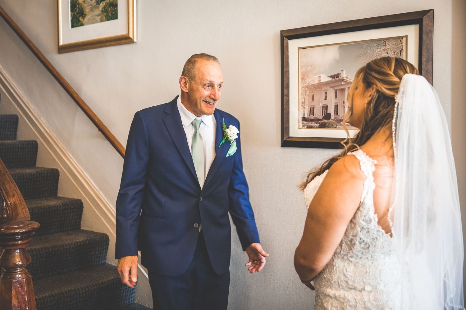 Emotional first look moment between couple in formal attire on a staircase during wedding day.
