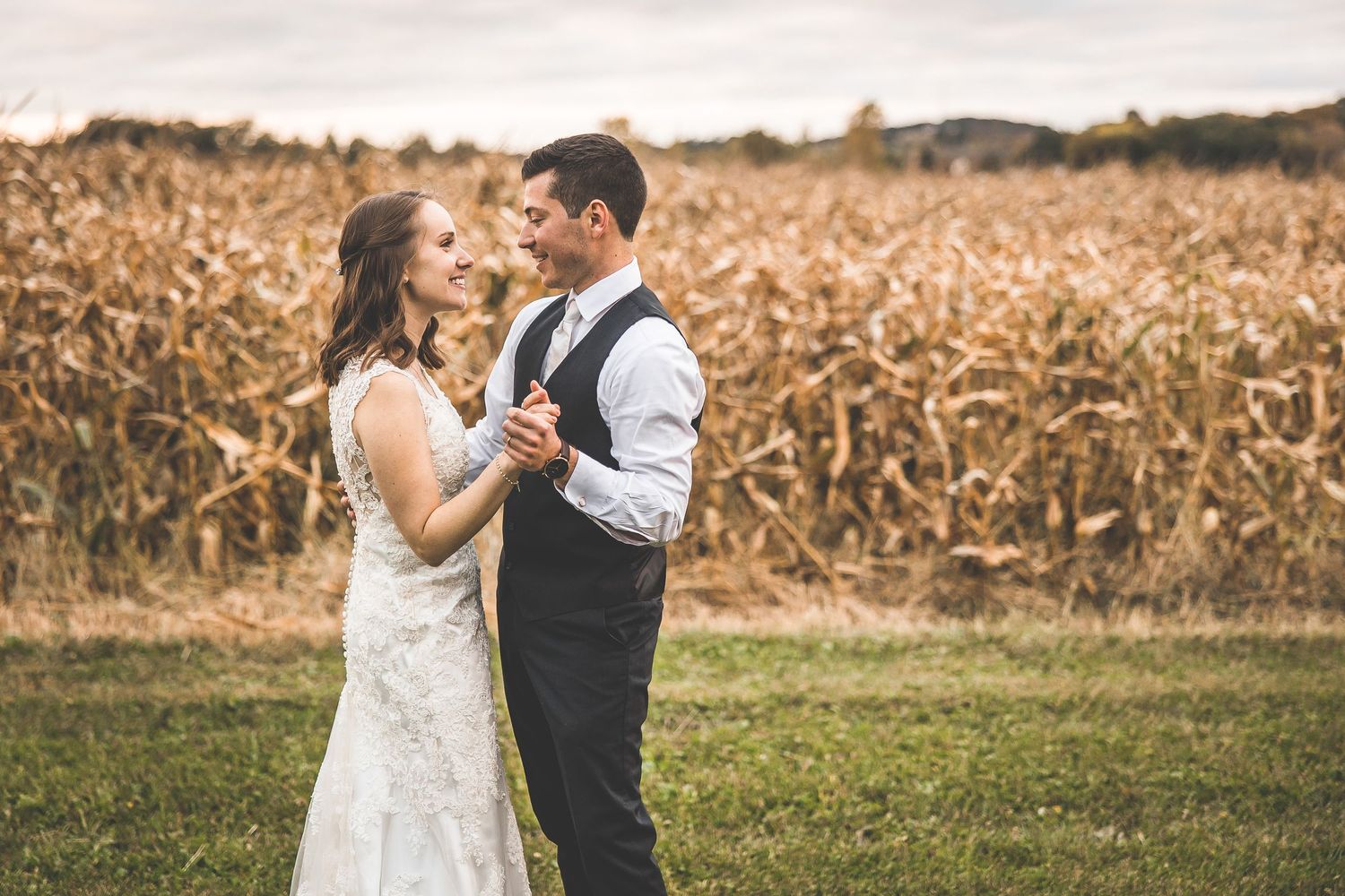 Wedding couple sharing an intimate dance moment against autumn cornfield backdrop.