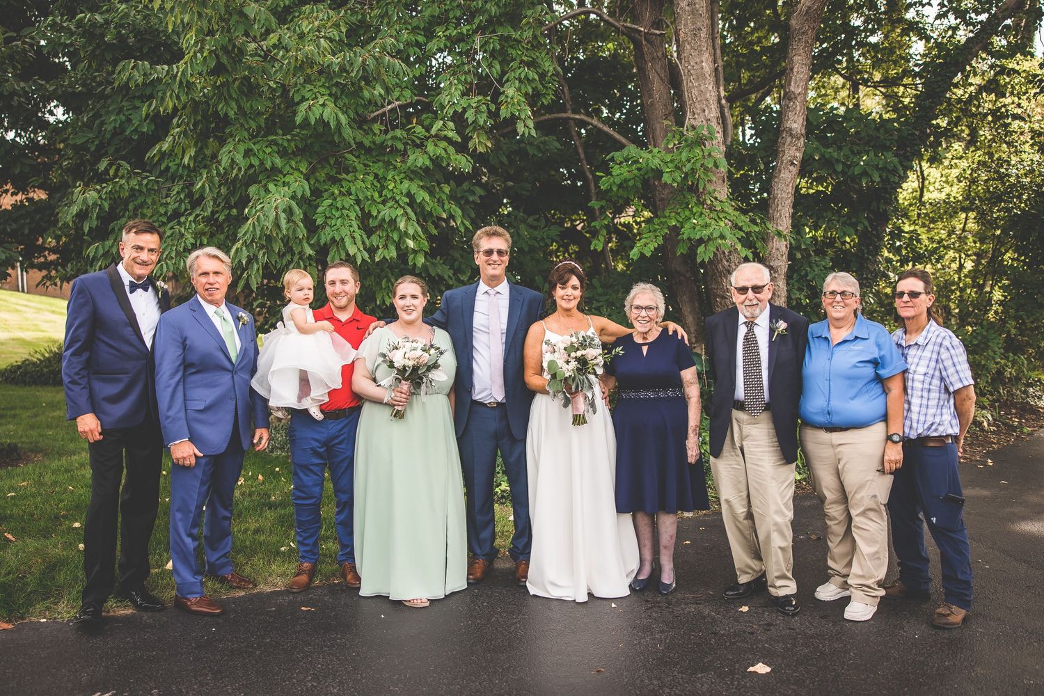 Wedding party and family members gathered for formal group portraits in outdoor garden setting.