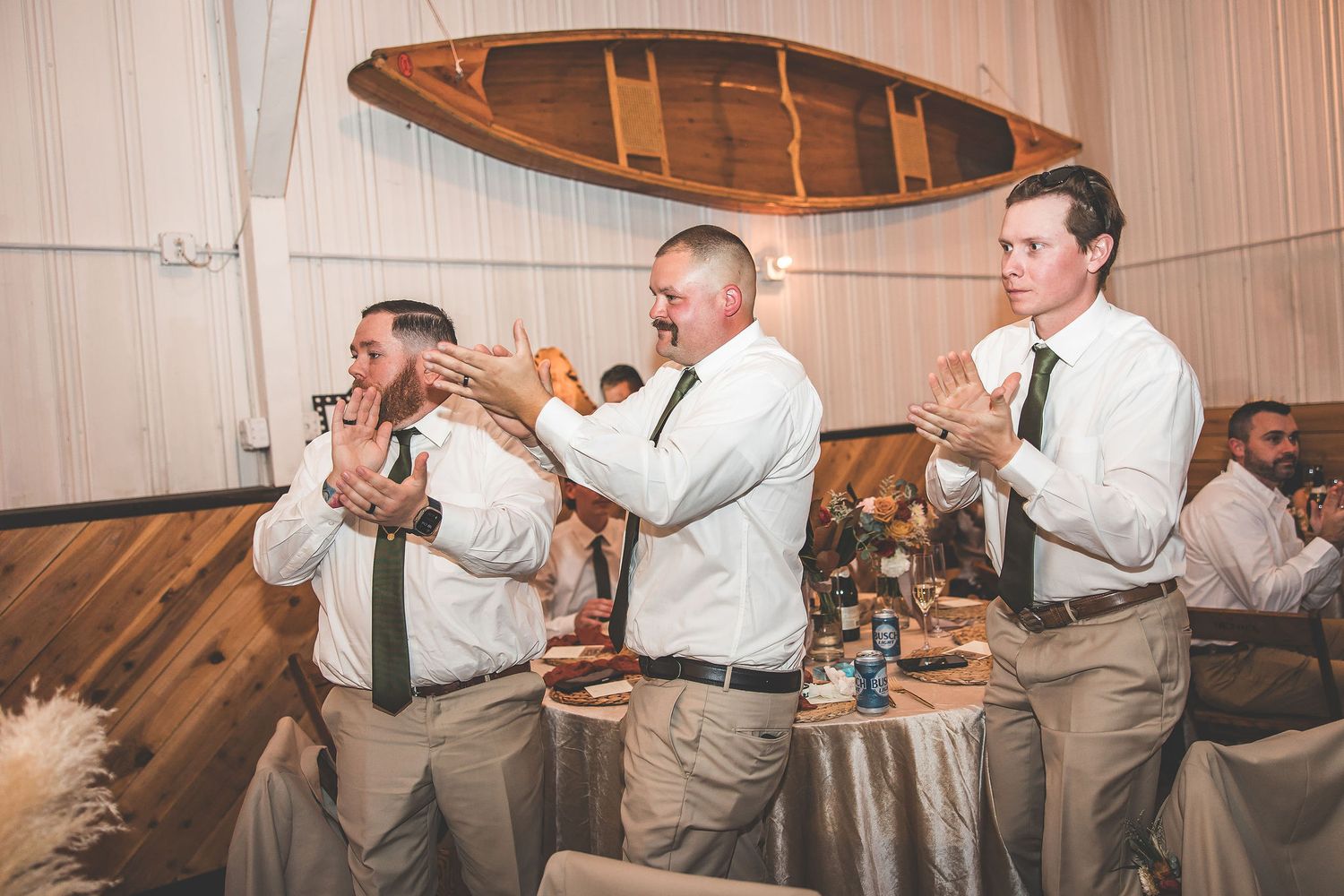 Groomsmen in light-colored suits perform synchronized dance moves at reception.