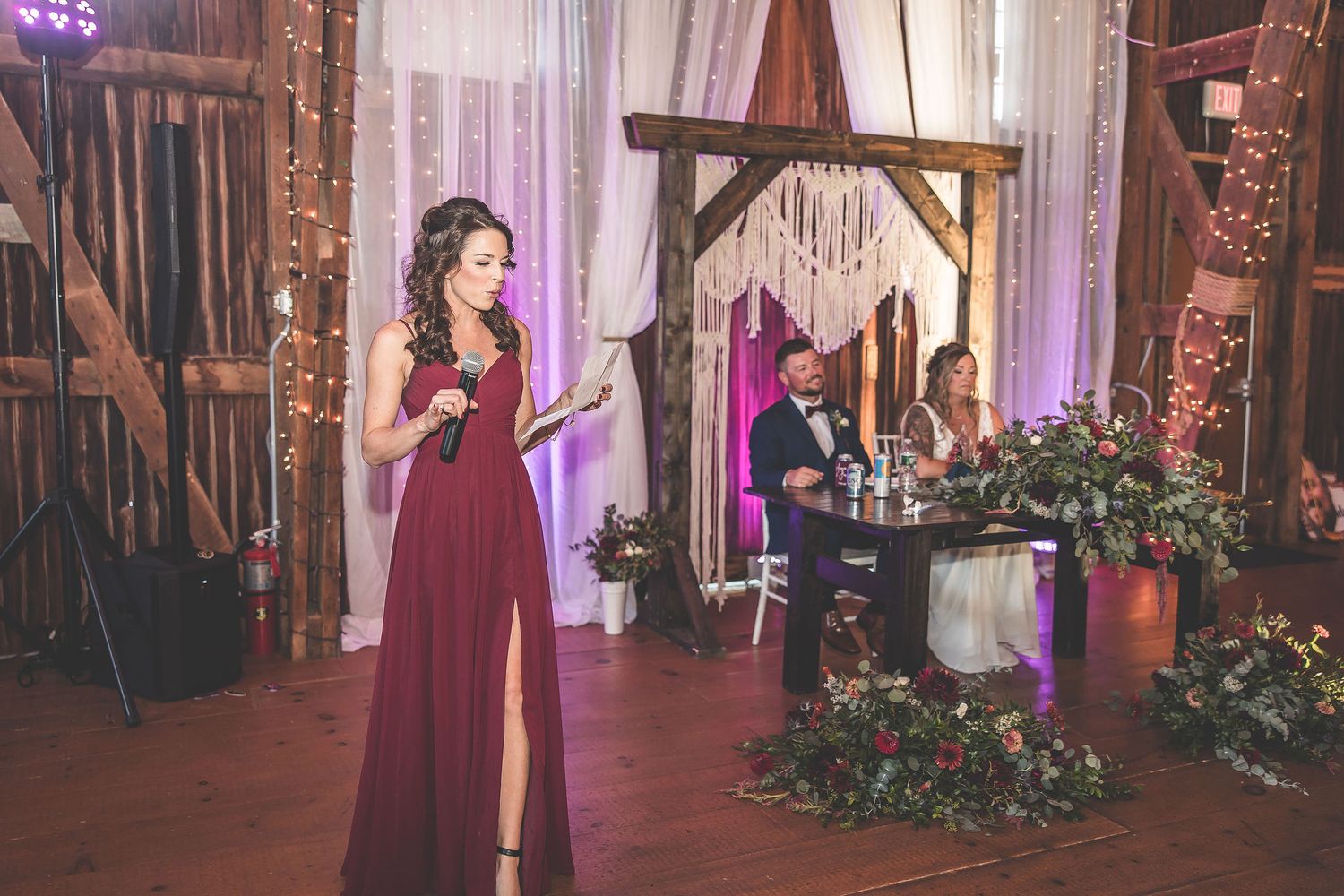 Wedding party dances in a beautifully decorated barn venue with purple lighting accents.