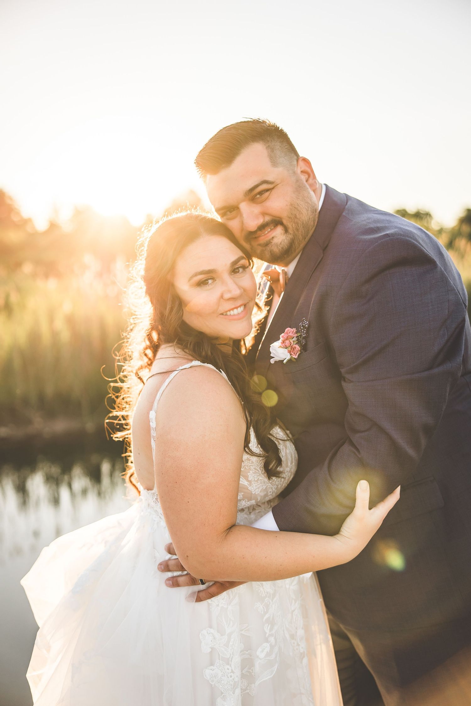 Sunset wedding portraits by a lake with golden light creating a dreamy atmosphere.