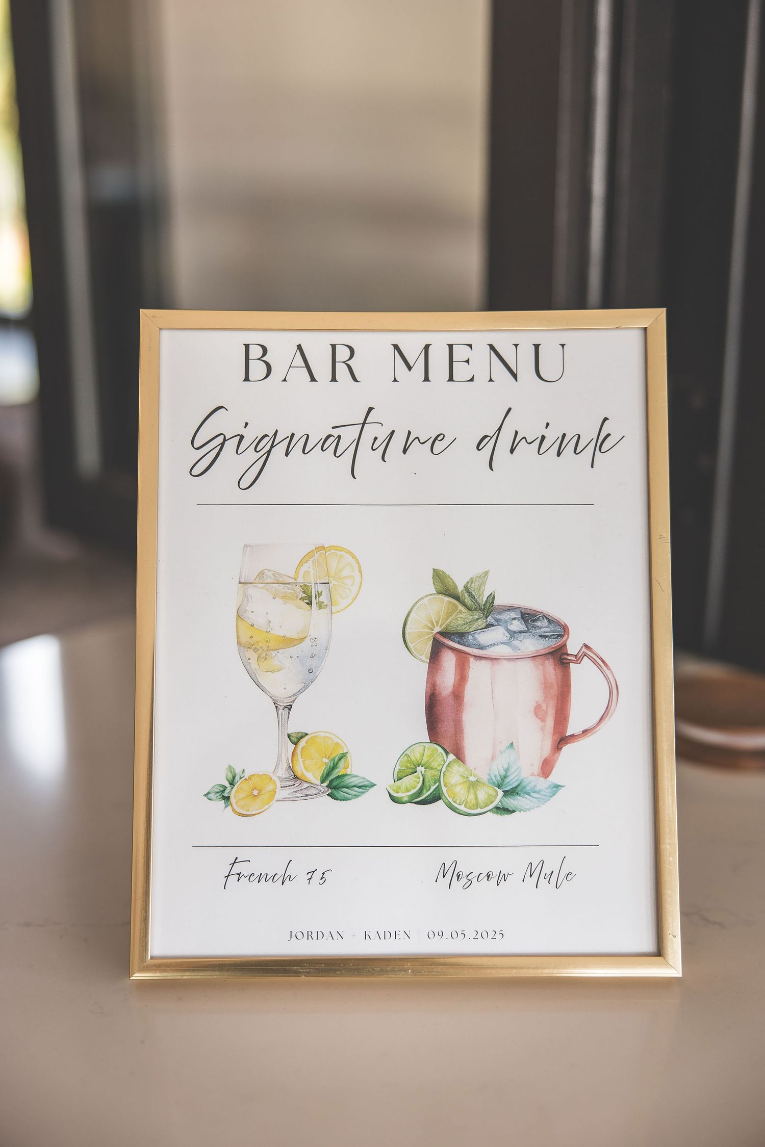 Watercolor bar menu signs displaying signature cocktails and drink options in gold frames.