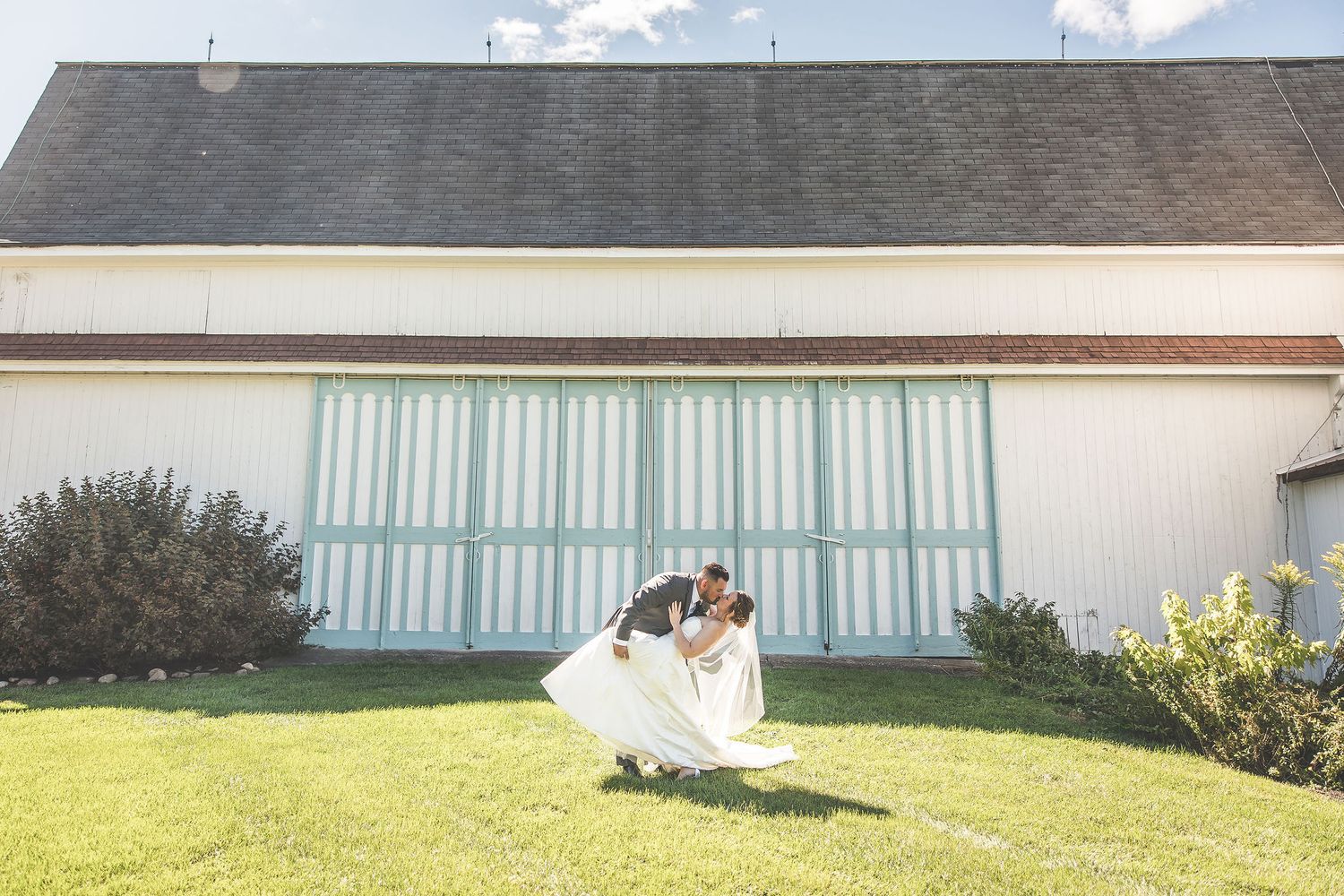 Panoramic wedding shots featuring farm buildings with silos under blue summer sky.