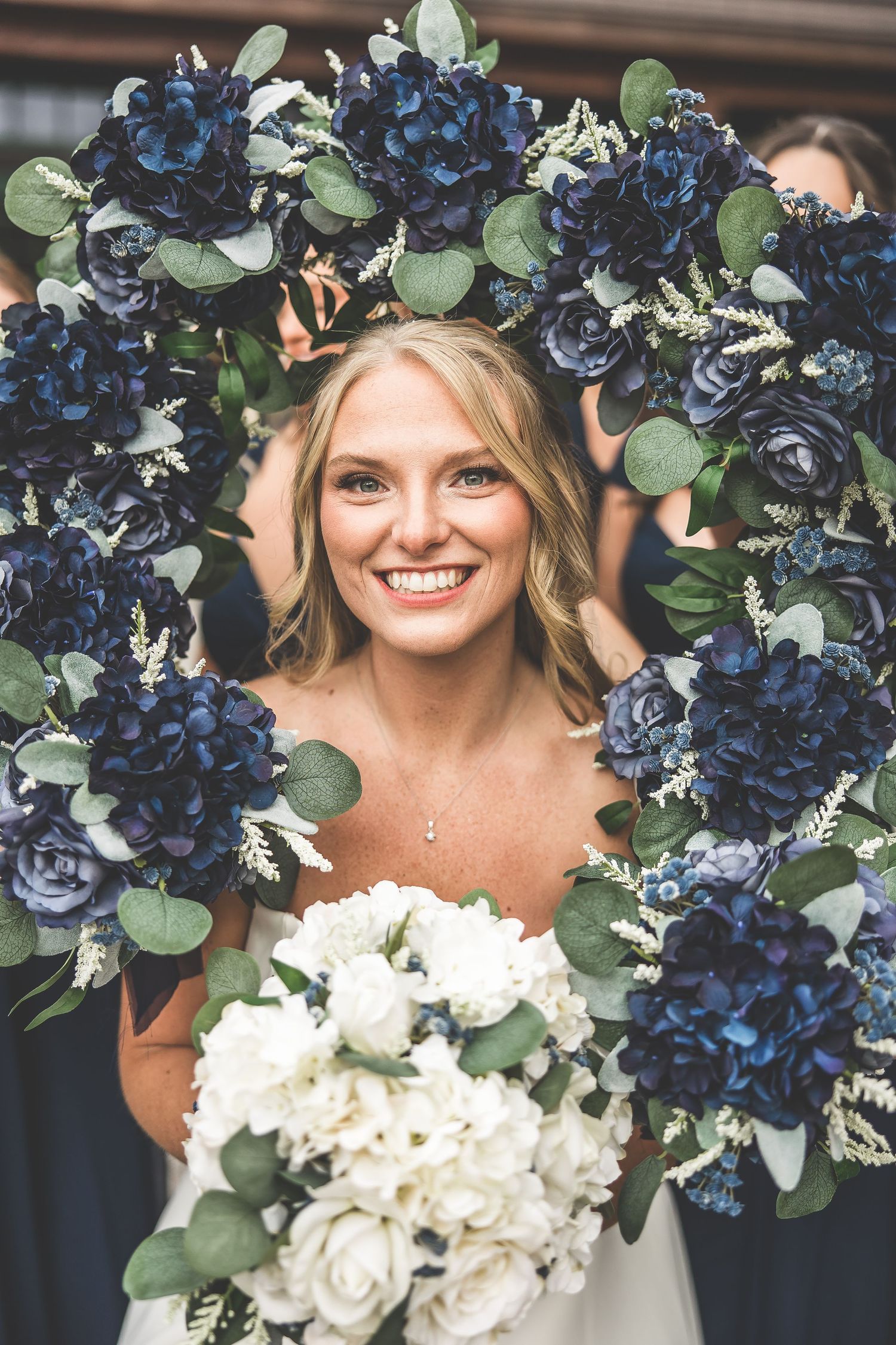 Beautiful wedding portrait framed by a wreath of deep blue flowers and eucalyptus leaves.