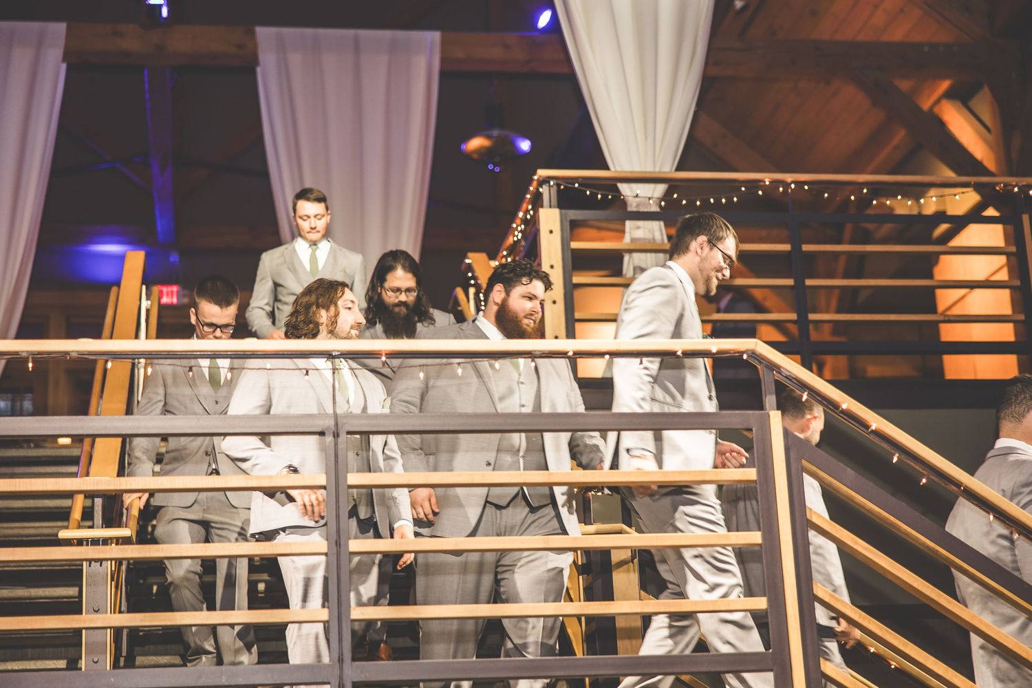 Wedding celebration in rustic venue with wooden beams and white draping.