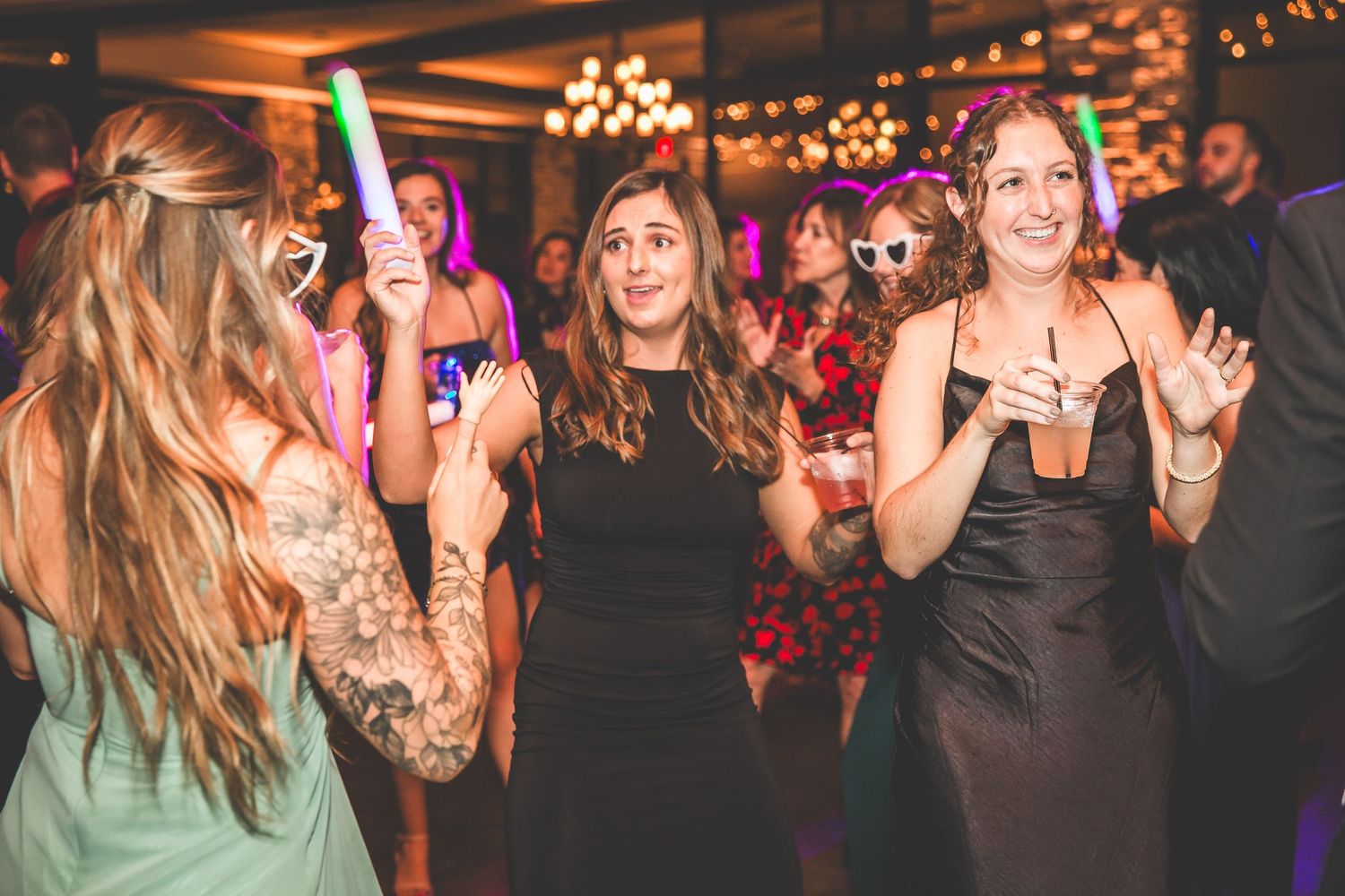 Wedding reception dance floor filled with guests enjoying themselves under ambient lighting.