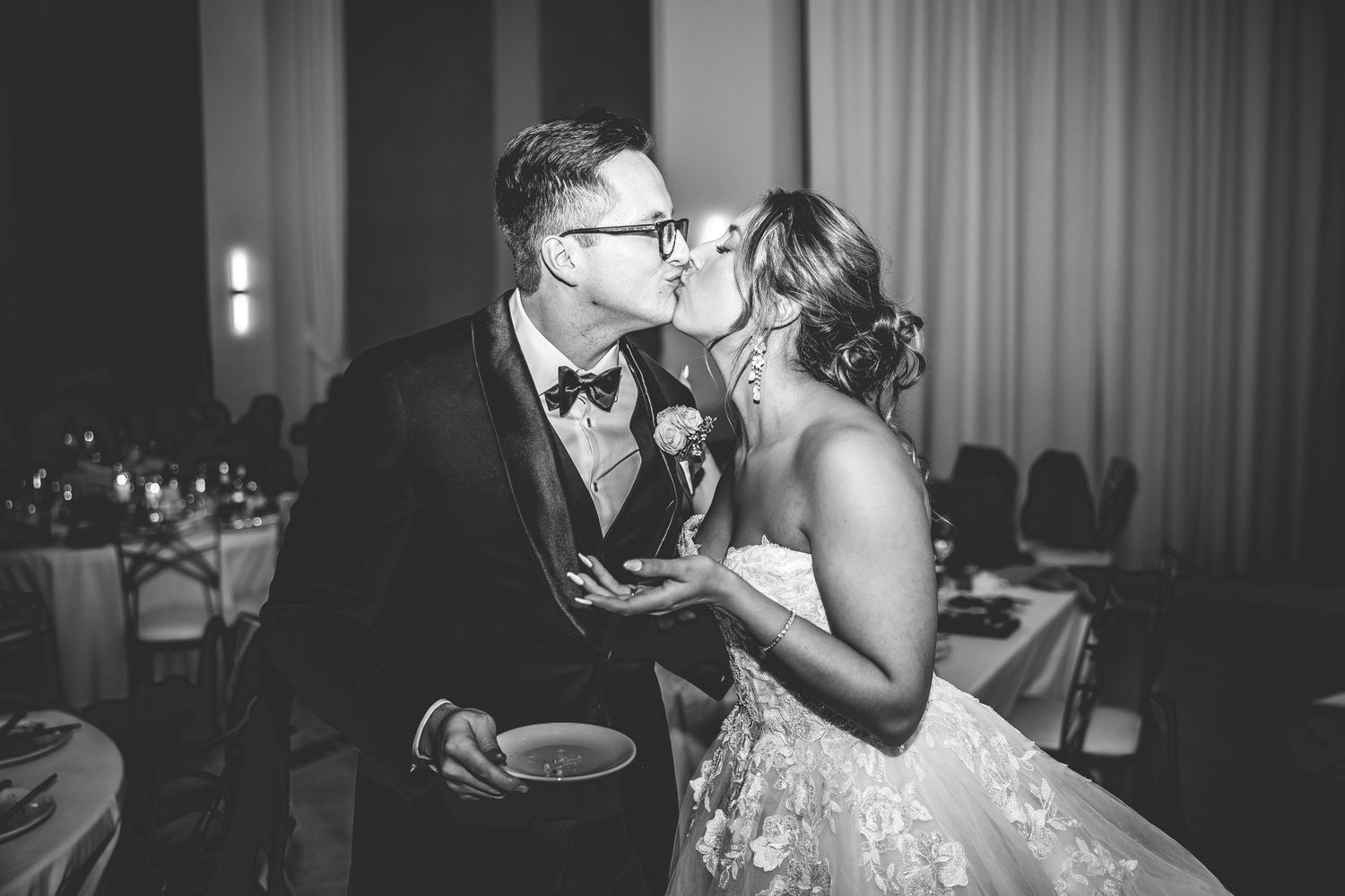 A romantic black and white wedding photo showing an intimate moment between newlyweds during their reception.