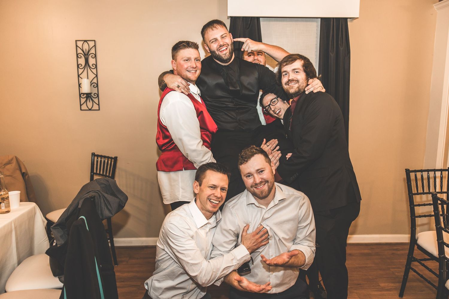 Wedding guests laughing and embracing during reception celebrations.