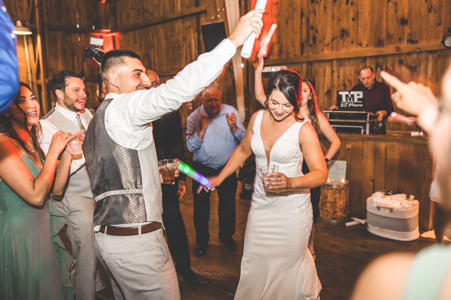Lively dance floor scene at a barn wedding reception with guests dancing in formal attire.